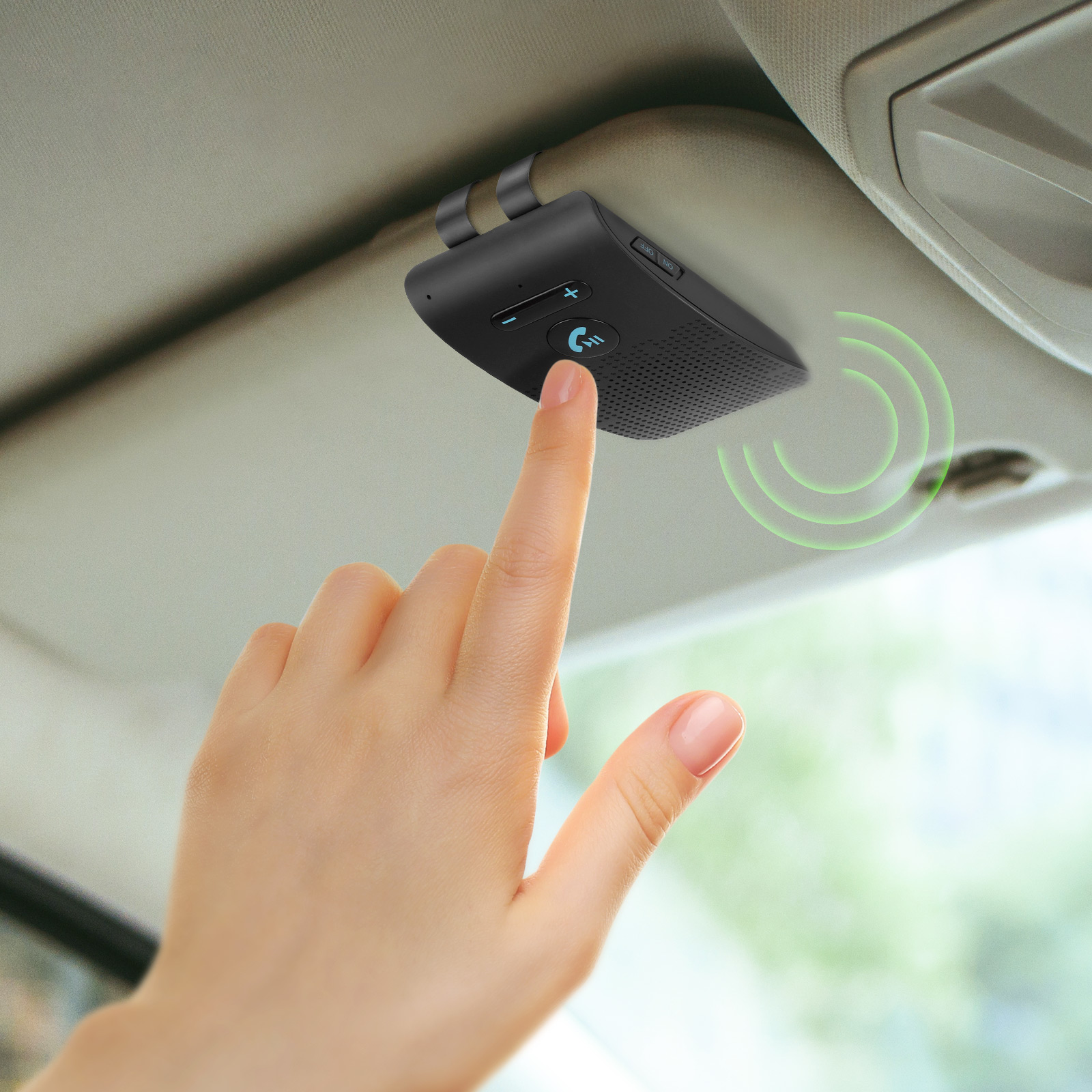 Schwarze Freisprecheinrichtung an der Sonnenblende eines Autos befestigt. Ein Finger berührt einen Knopf. Grüne Welle.