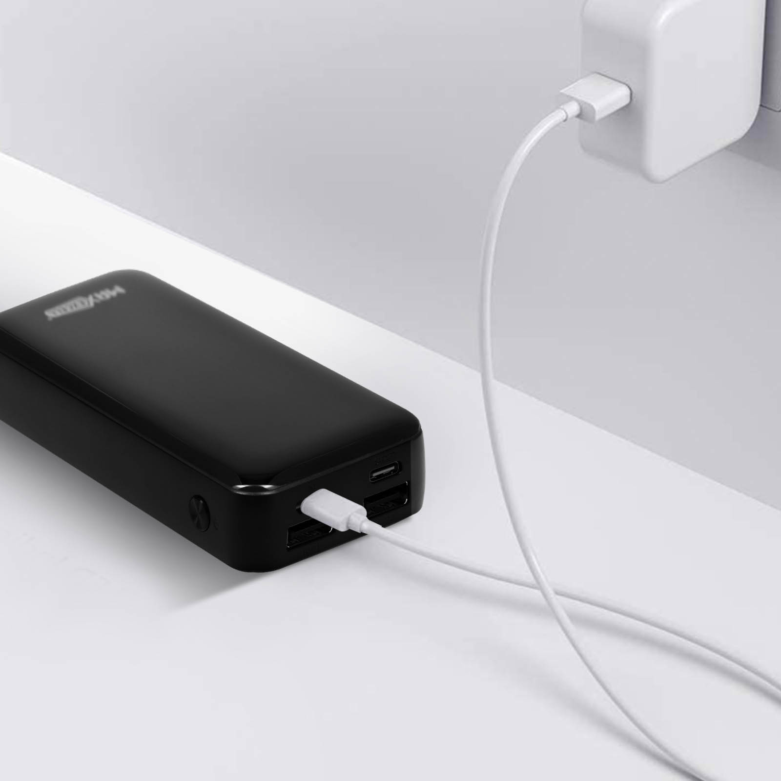 Schwarze Powerbank mit weißem Ladekabel. Weißer Hintergrund und ein weißer Wandadapter.