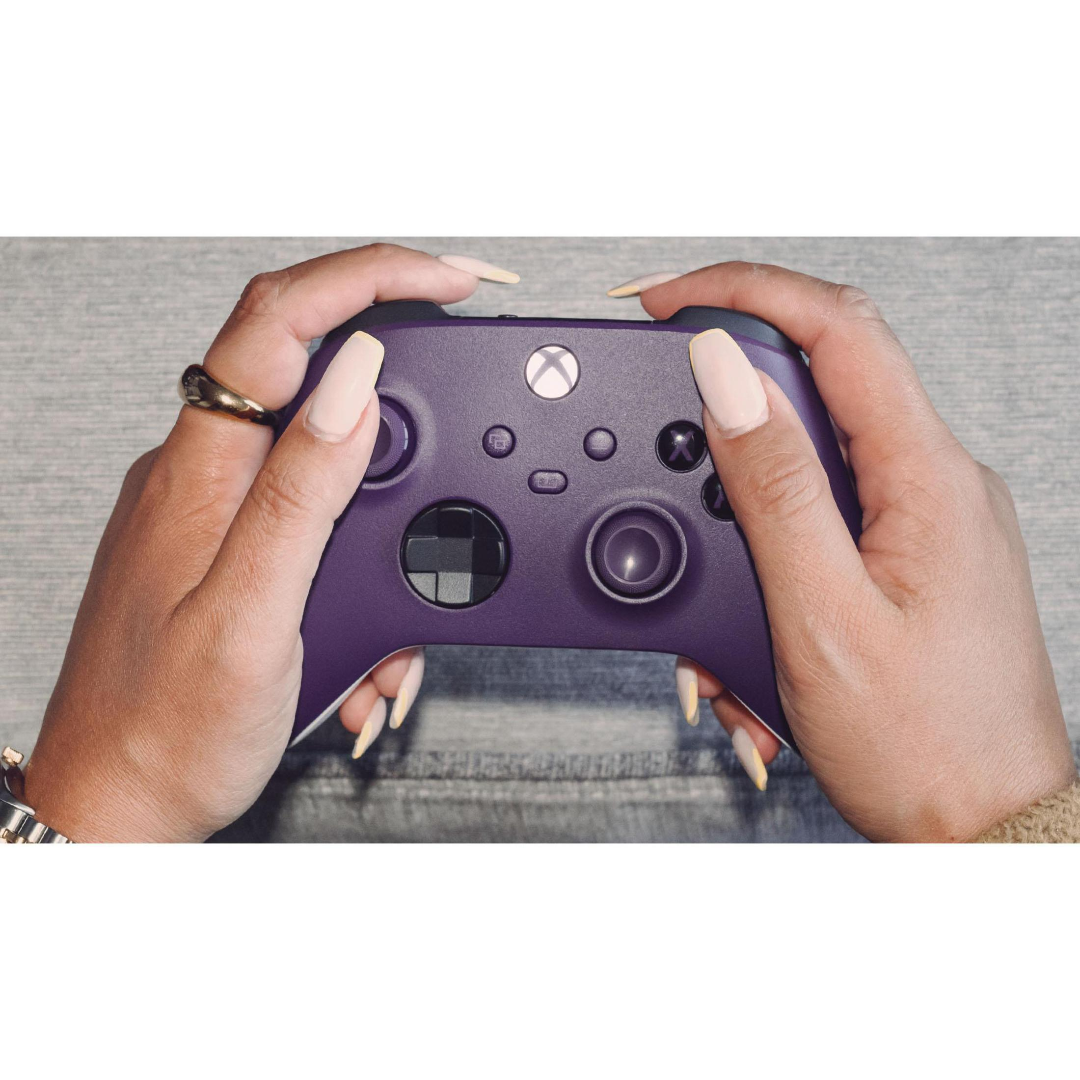 Persona che tiene un controller Xbox viola con unghie lunghe e curate e un anello d'oro.