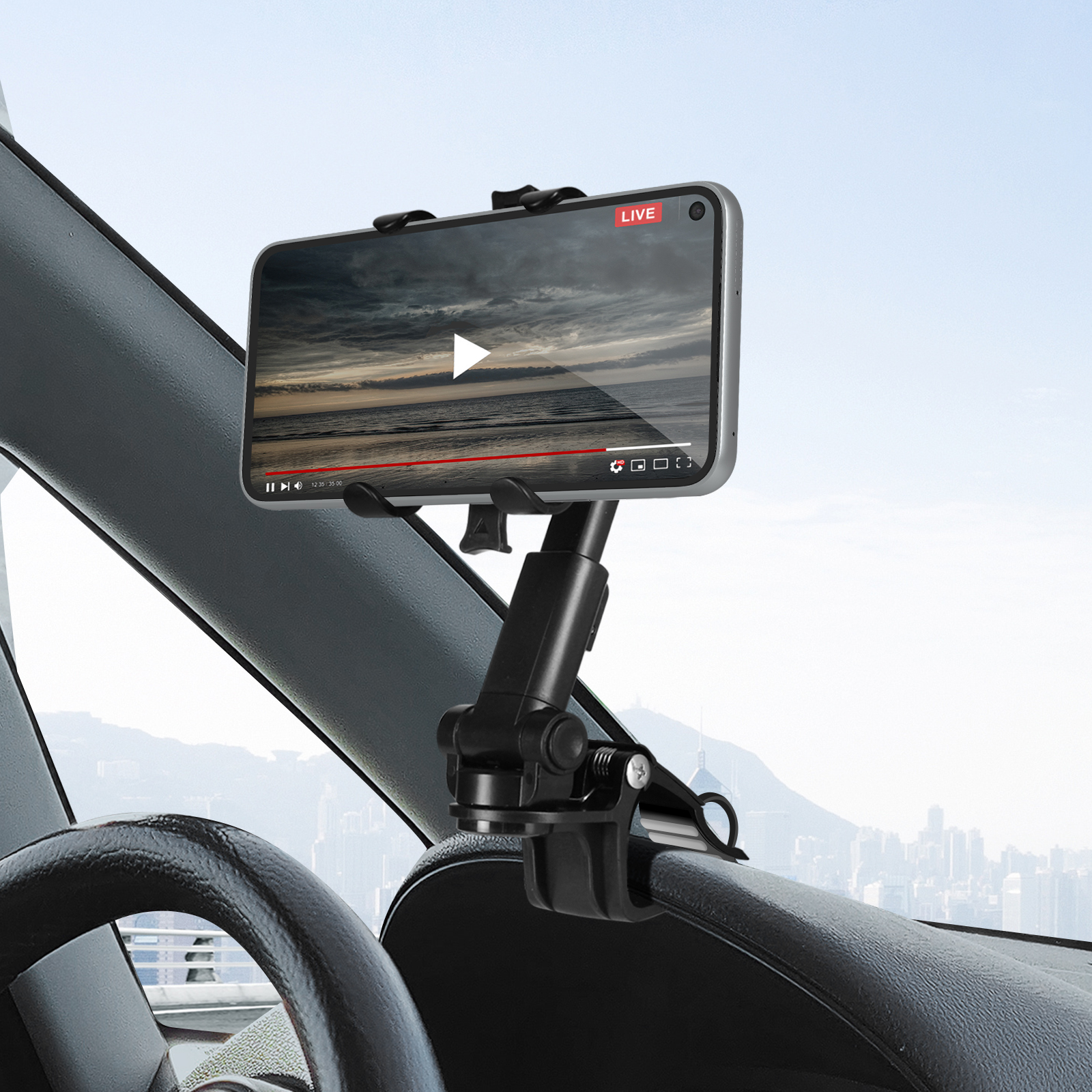 Telefono in supporto auto mostra video. Interno auto con volante e città sullo sfondo.