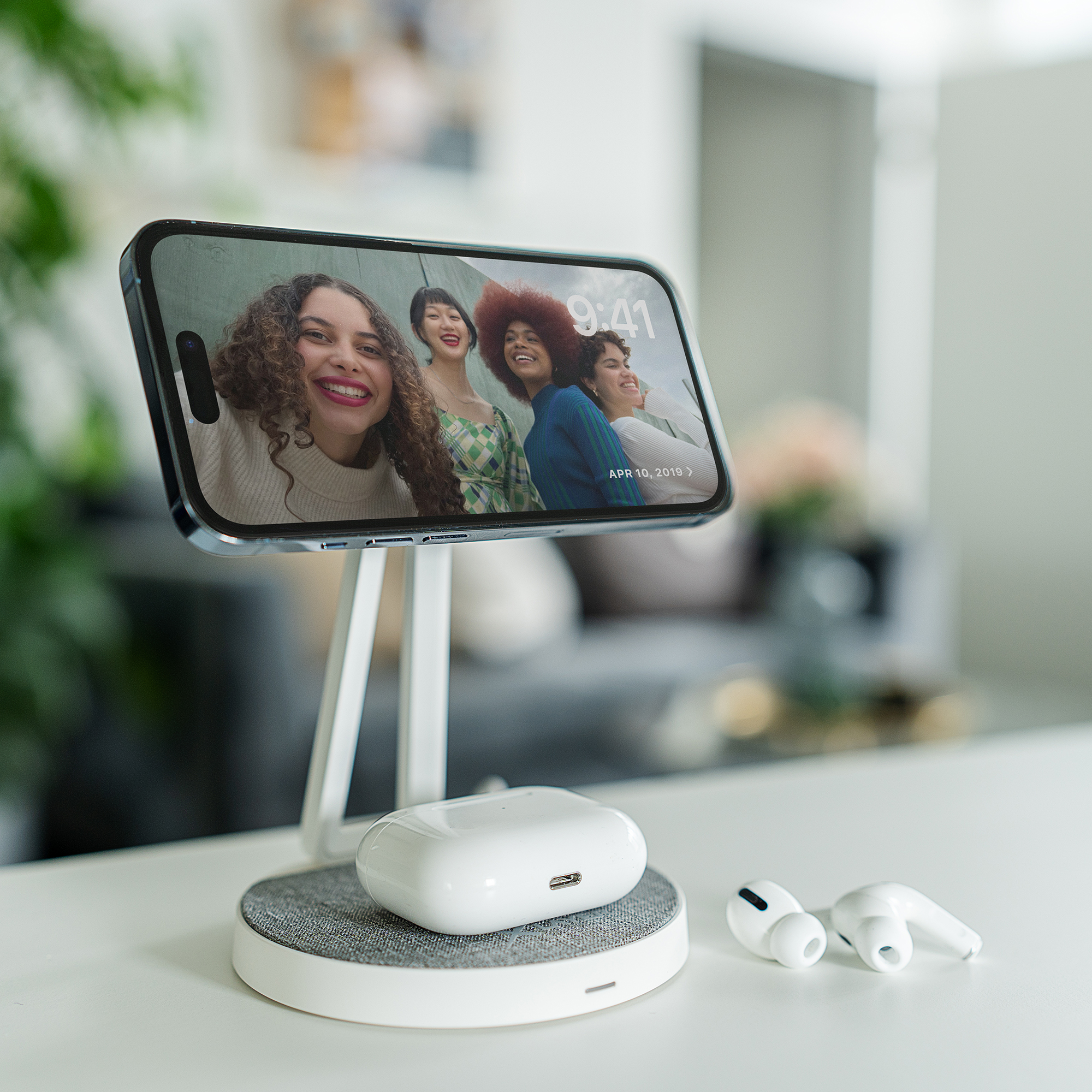 Smartphone auf Ständer mit kabellosem Laden. AirPods auf der Basis, Selfie auf dem Bildschirm.