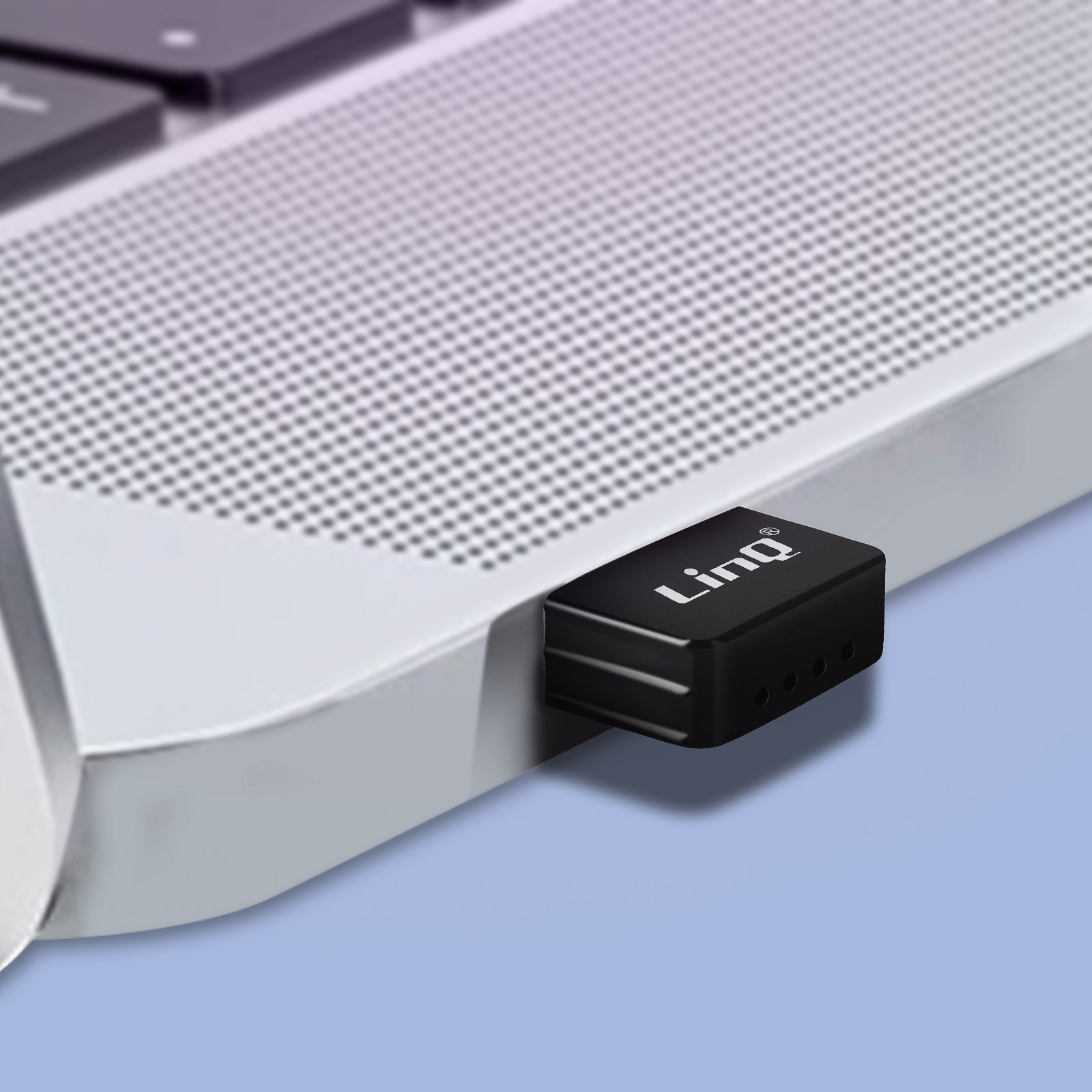 Adaptador USB negro conectado a una computadora portátil. Tiene el logotipo 'LinQ' y tres luces.