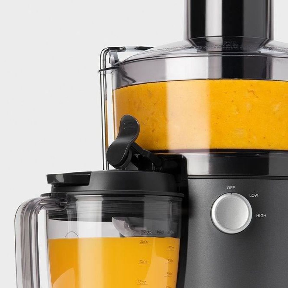 Centrifuga con succo d'arancia in un contenitore di vetro. La centrifuga è nera e ha un pannello di controllo.
