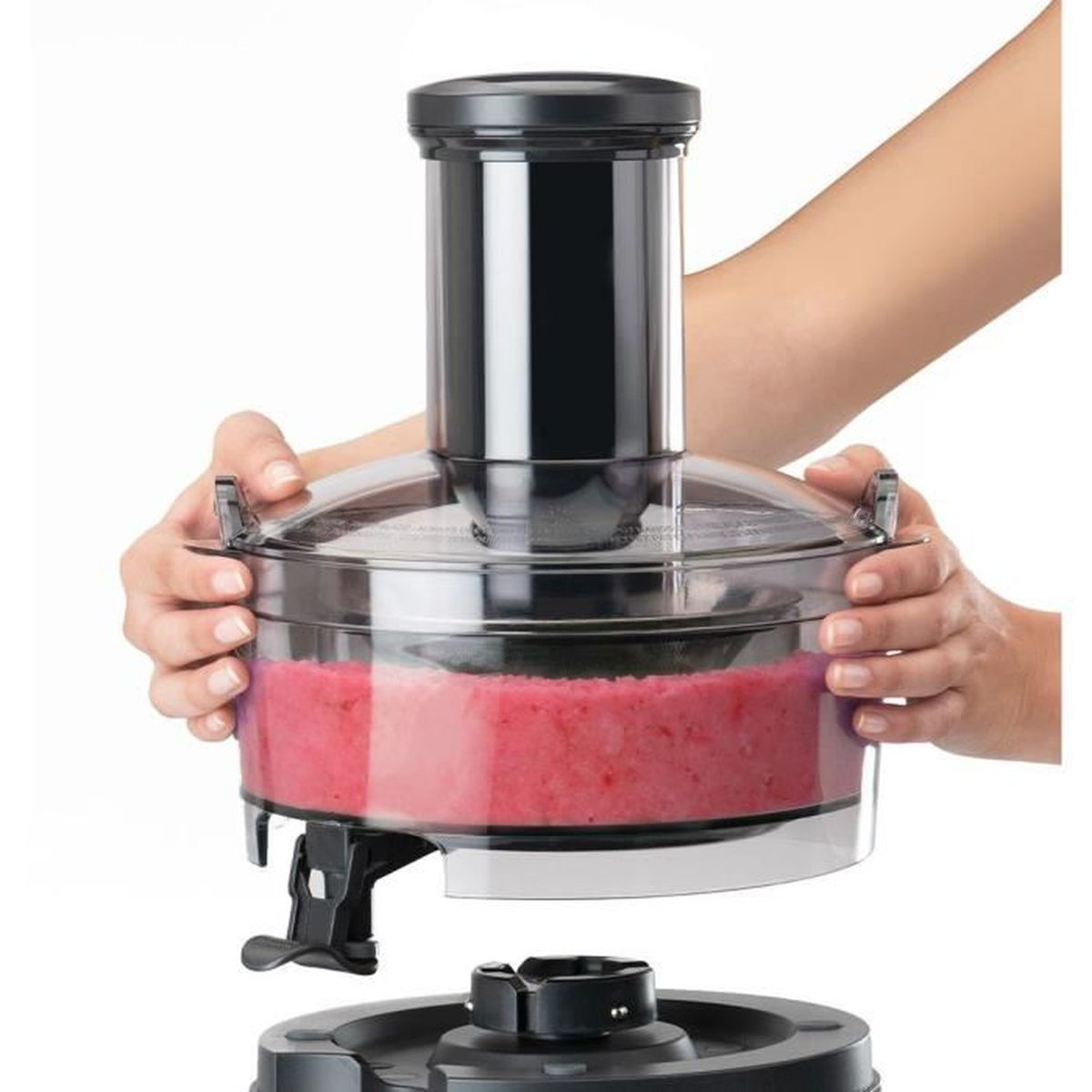 Una donna tiene in mano un robot da cucina. L'apparecchio contiene una sostanza rosa miscelata.