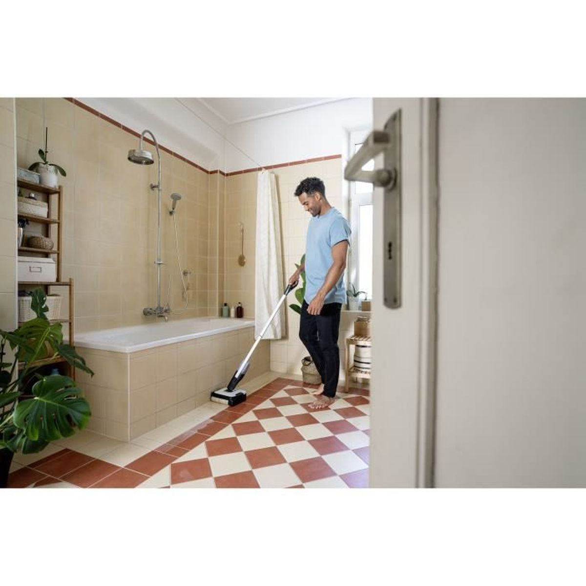Uomo che pulisce il pavimento del bagno con un pulitore. Bagno con pavimento a scacchi rosso e bianco.