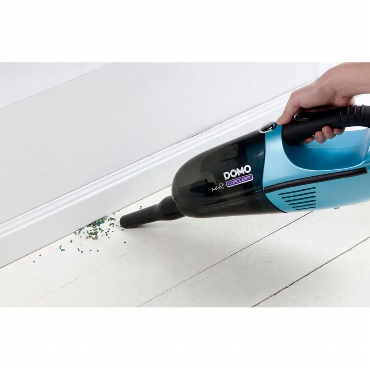 Mano usando una aspiradora inalámbrica azul y negra. Limpiando un piso de madera blanco.