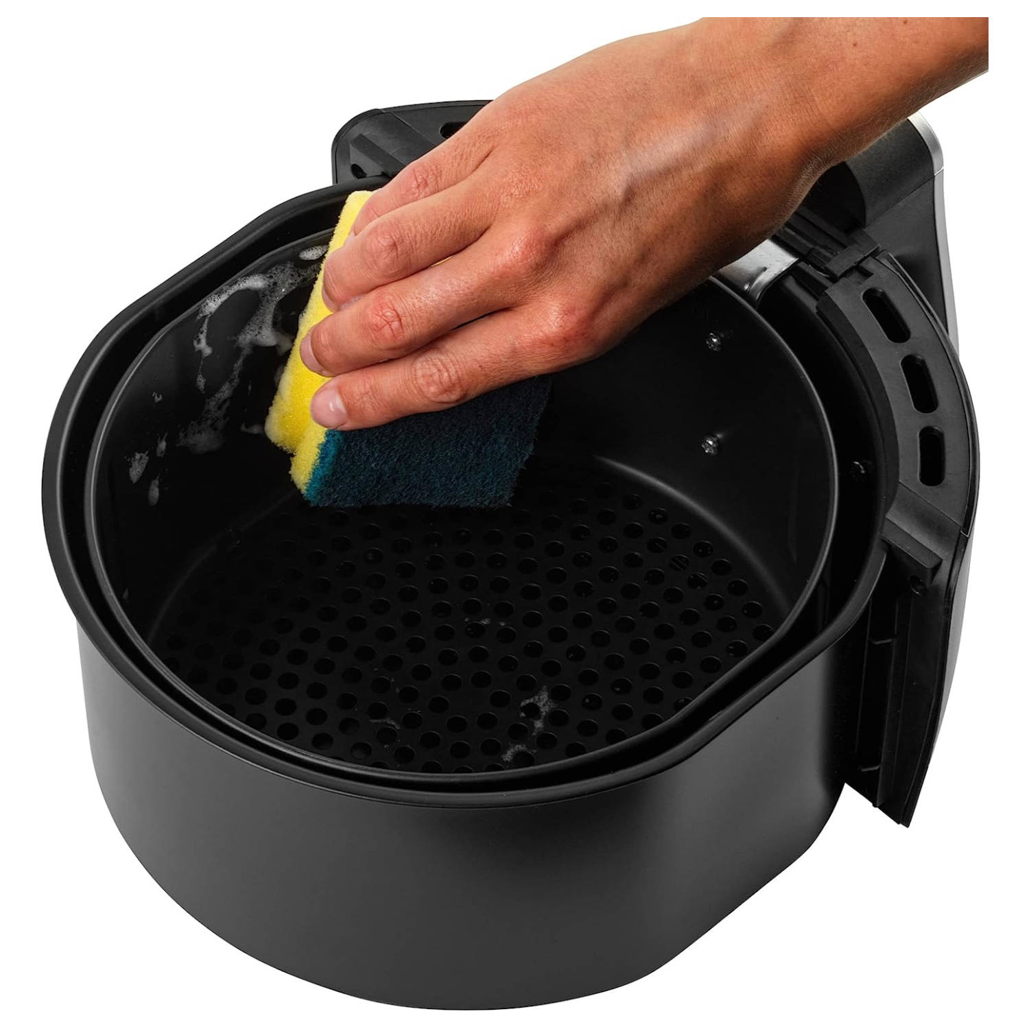 Una mano pulisce una friggitrice ad aria con una spugna, all'interno del cestello nero.