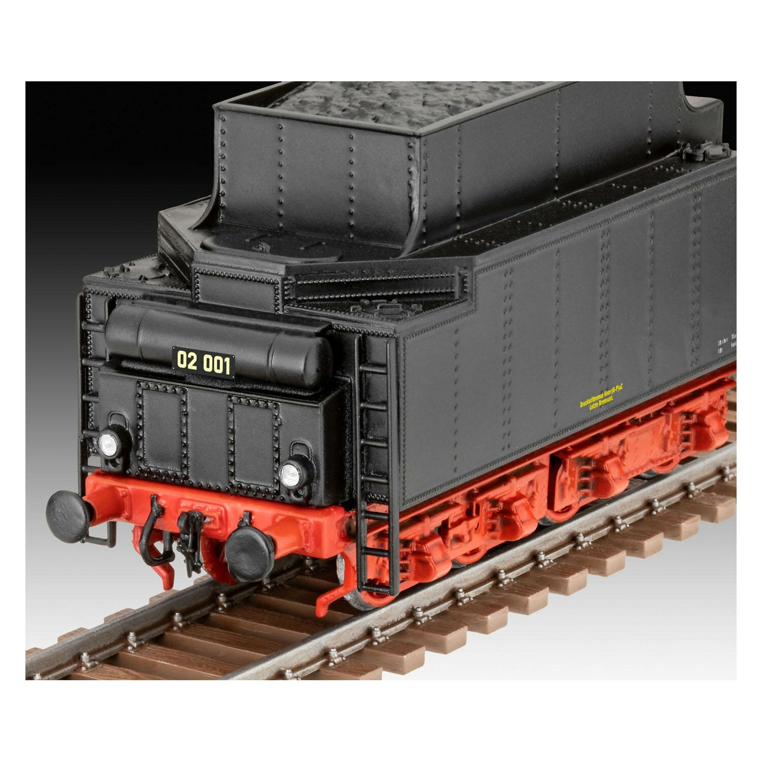 Zwarte modeltreinlocomotief op rails. Rode en zwarte details. Donkere achtergrond. Close-up.