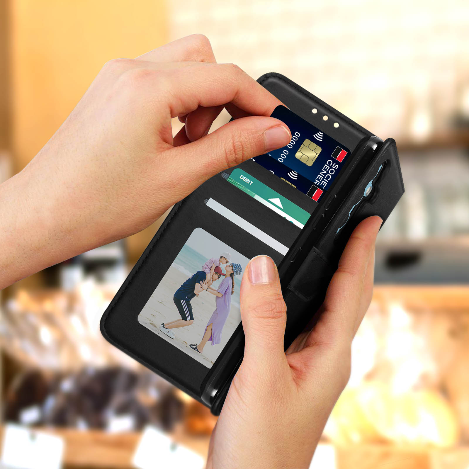 Hände öffnen eine schwarze Telefonhülle mit Fotos und Kreditkarten im Inneren.