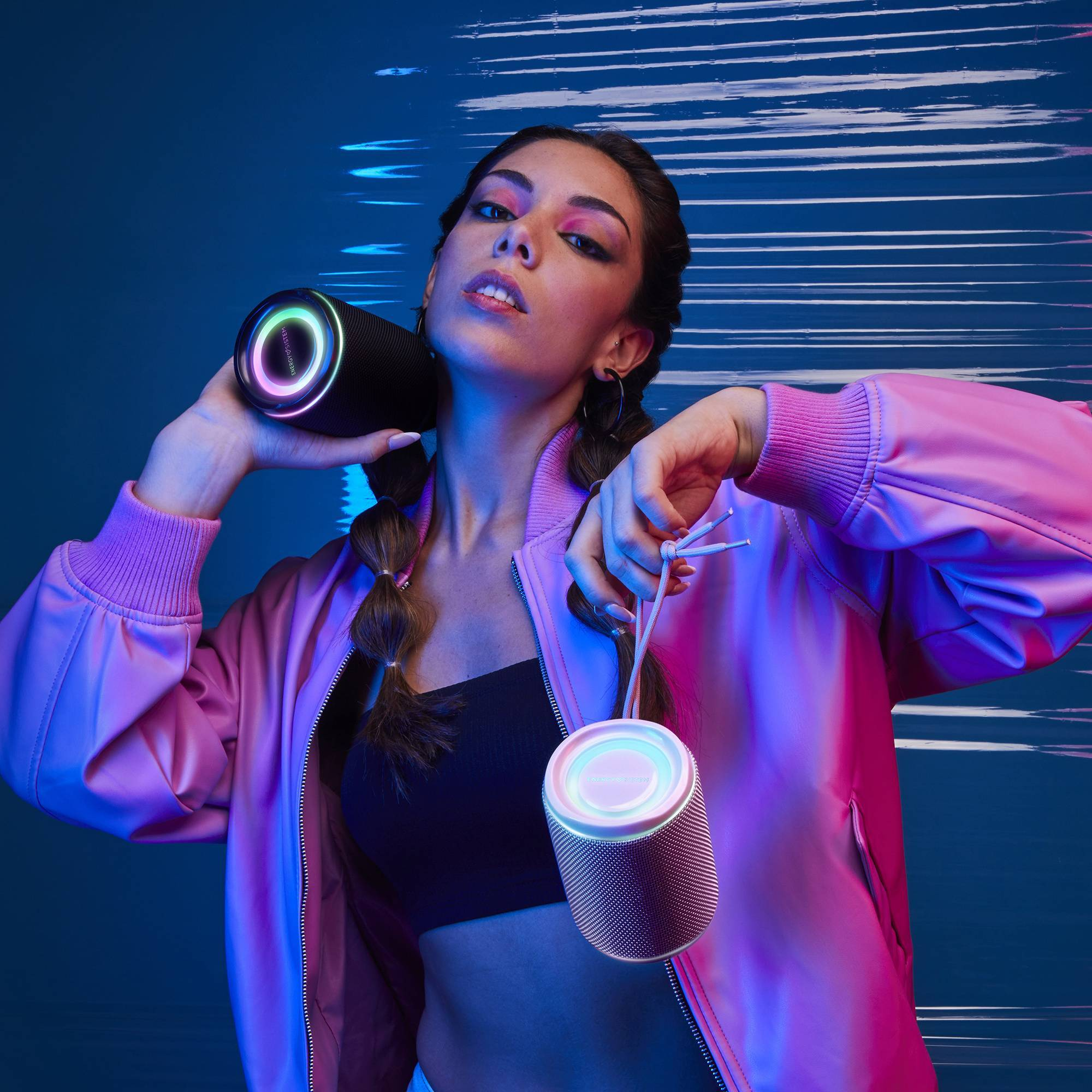Kobieta trzyma dwa czarne głośniki cylindryczne z kolorowymi światłami.