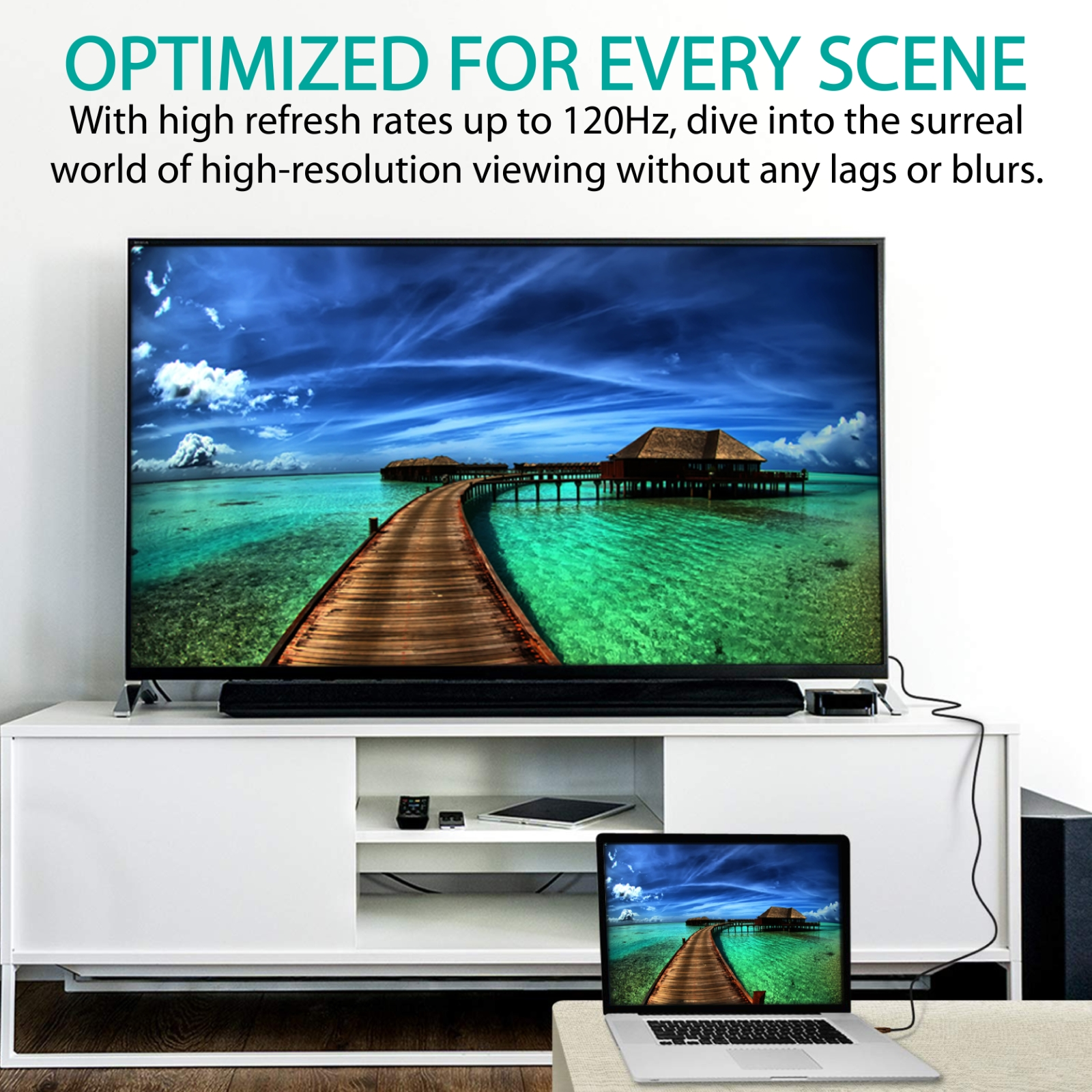 Un televisor que muestra una hermosa escena de playa. Hay un portátil y una barra de sonido en un mueble blanco.