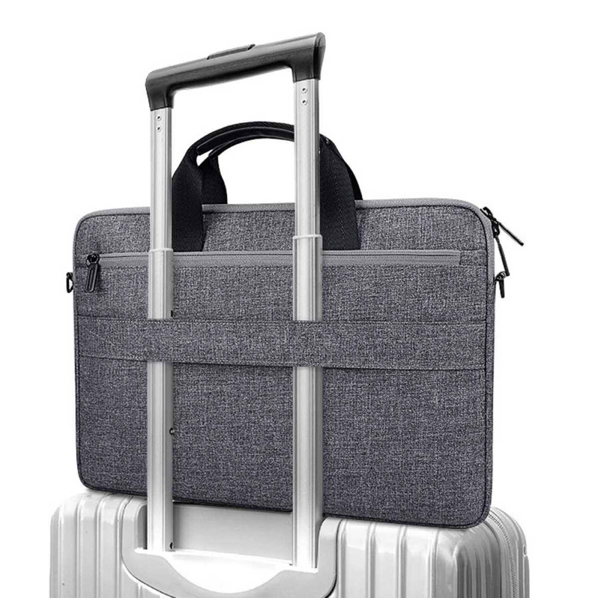 Eine graue Laptoptasche liegt auf einem Koffer. Die Tasche hat einen Griff und einen Reißverschluss. Der Hintergrund ist weiß.