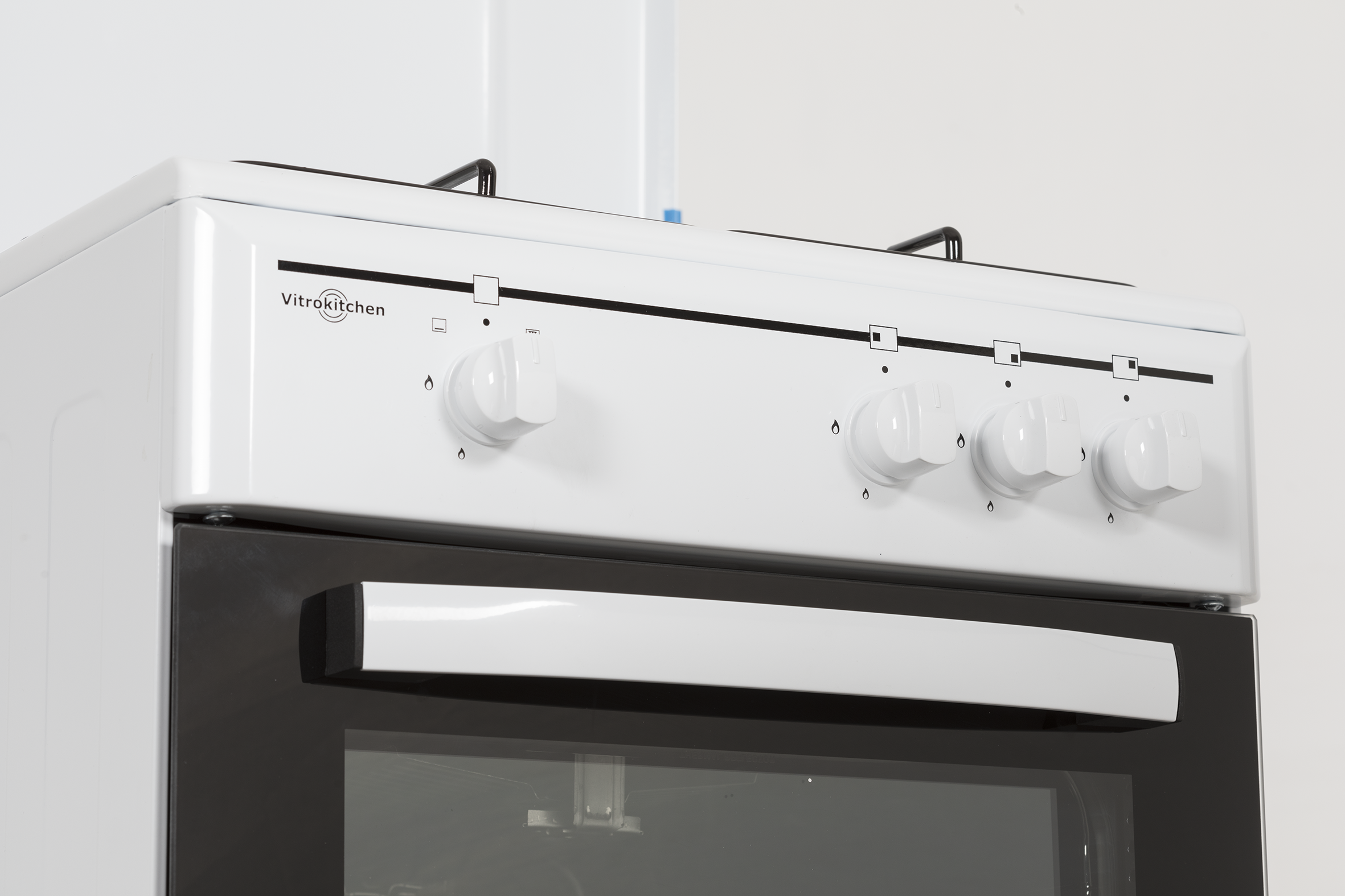 Una estufa blanca VitroKitchen con cuatro mandos y una puerta de horno negra.