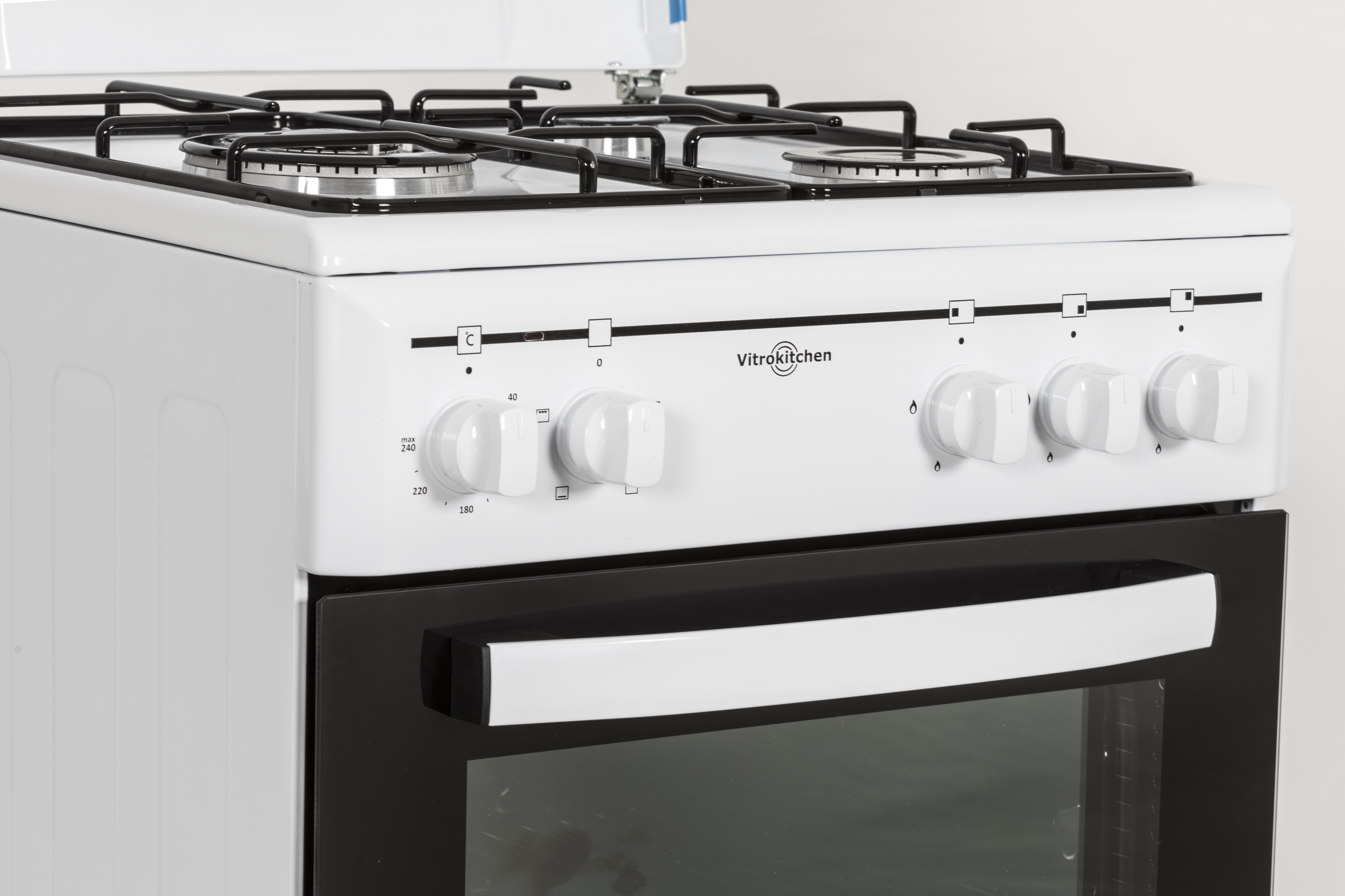 Primer plano de una estufa VitroKitchen blanca, con perillas y una puerta de horno negra.