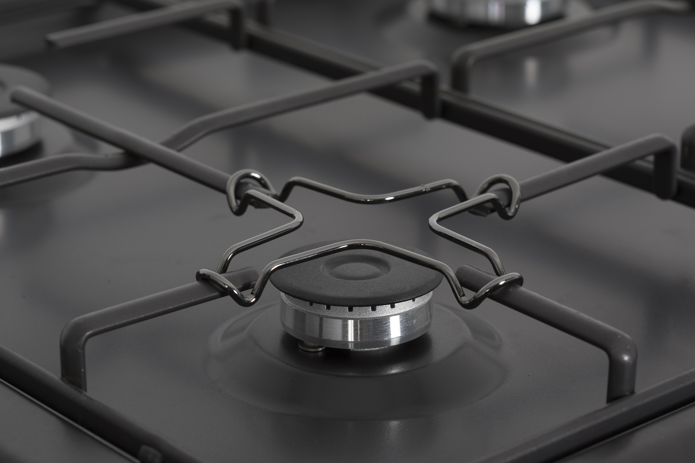 Primer plano de un quemador de cocina de gas negro. Anillo de llama circular y soportes negros. Superficie negra.