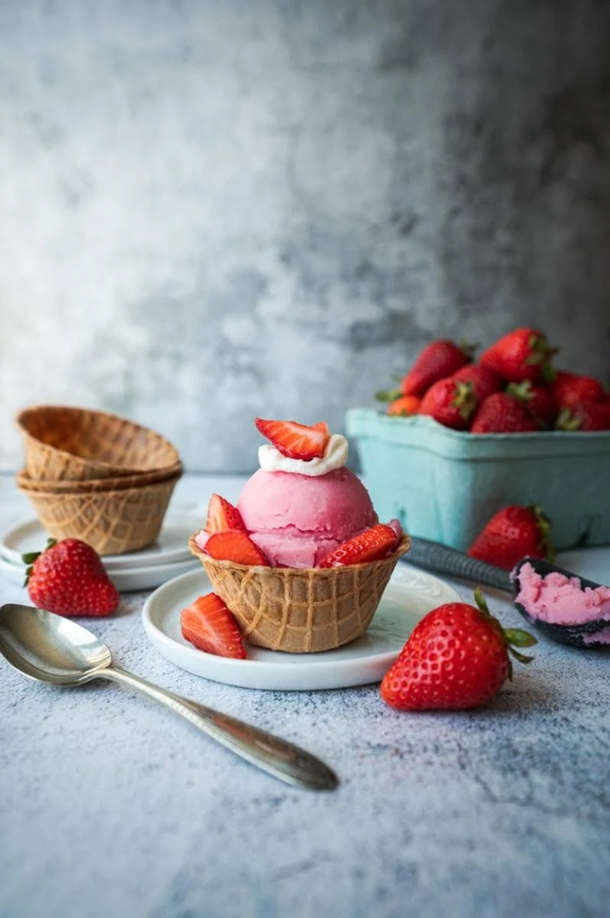 Helado de fresa en un cuenco de gofre con fresas en una mesa.
