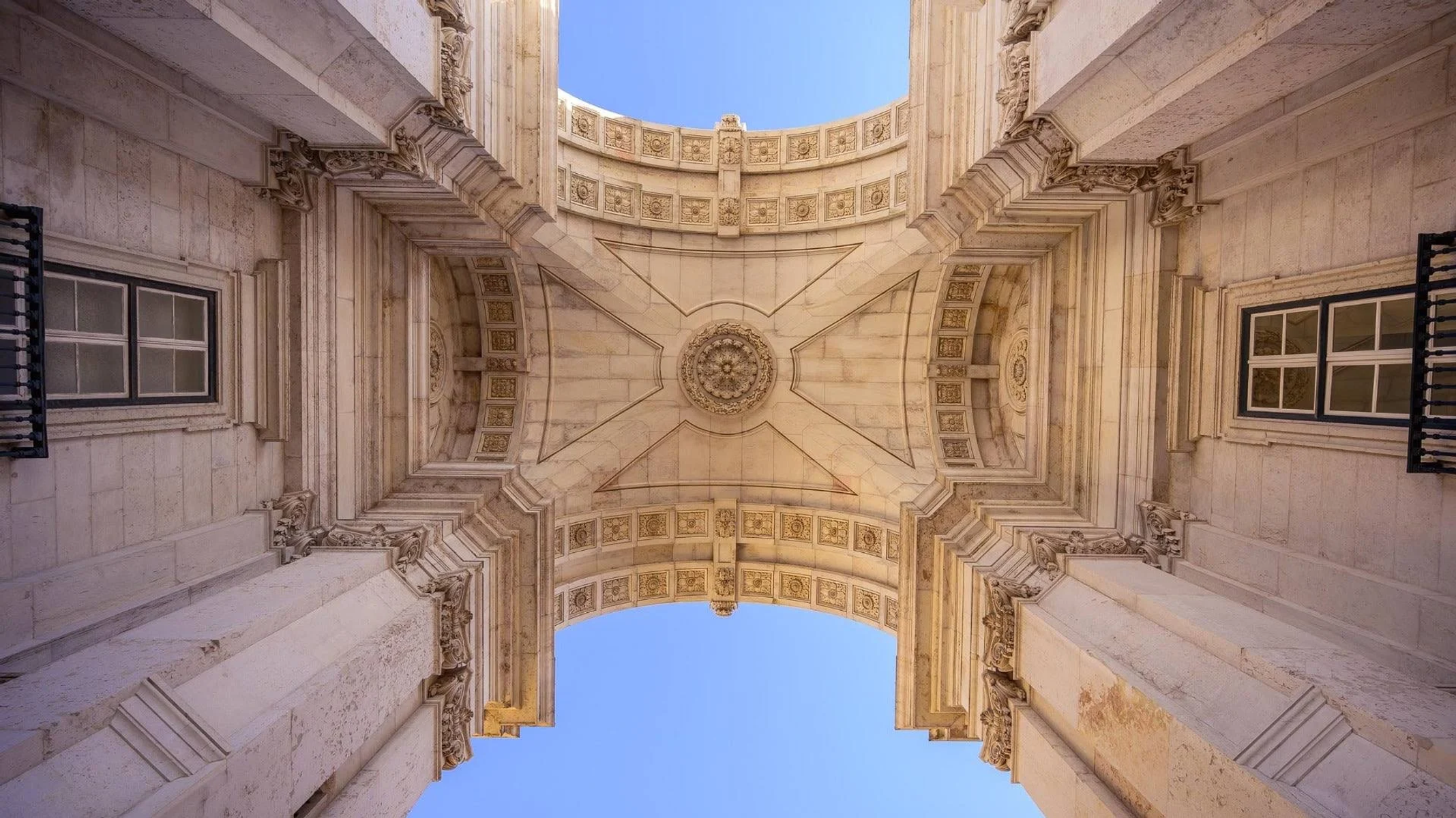 Toma de ángulo bajo de un arco de techo ornamentado. El cielo es azul y visible a través de la parte superior.