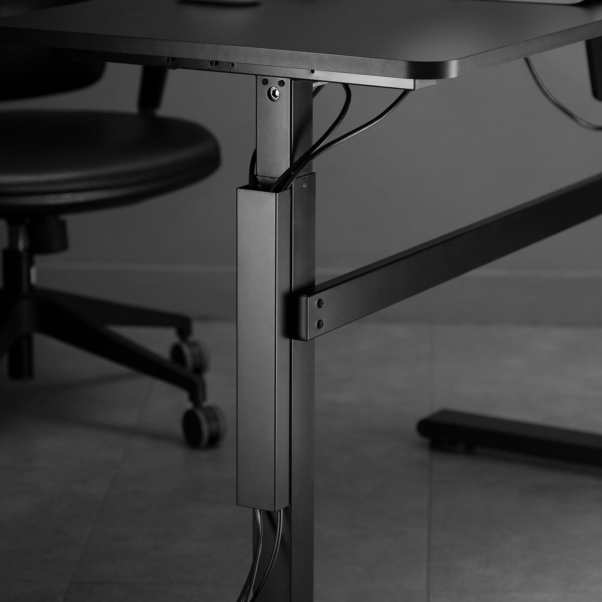 Escritorio negro con cables y silla negra. Entorno de oficina moderno y minimalista.
