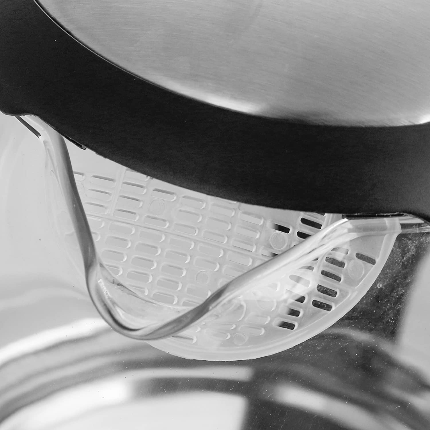 Close-up shot of a white and transparent spout of a kettle. The spout has a filter inside.