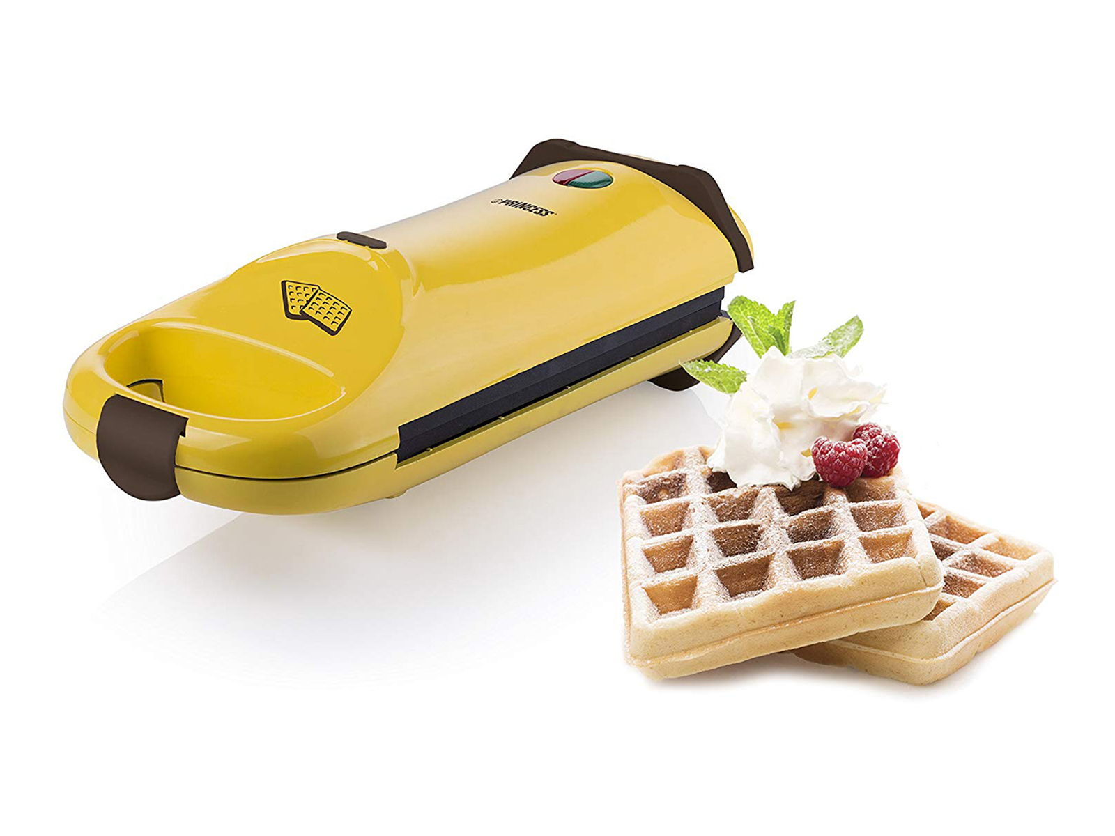 Macchina per waffle gialla con waffle e panna montata, lamponi e foglie di menta.