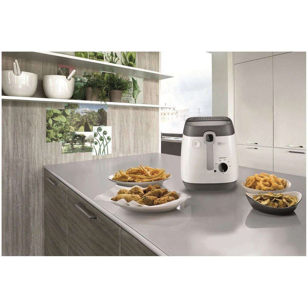 Scena kuchenna: frytownica z smażonym jedzeniem na talerzach i półka z roślinami i miskami.