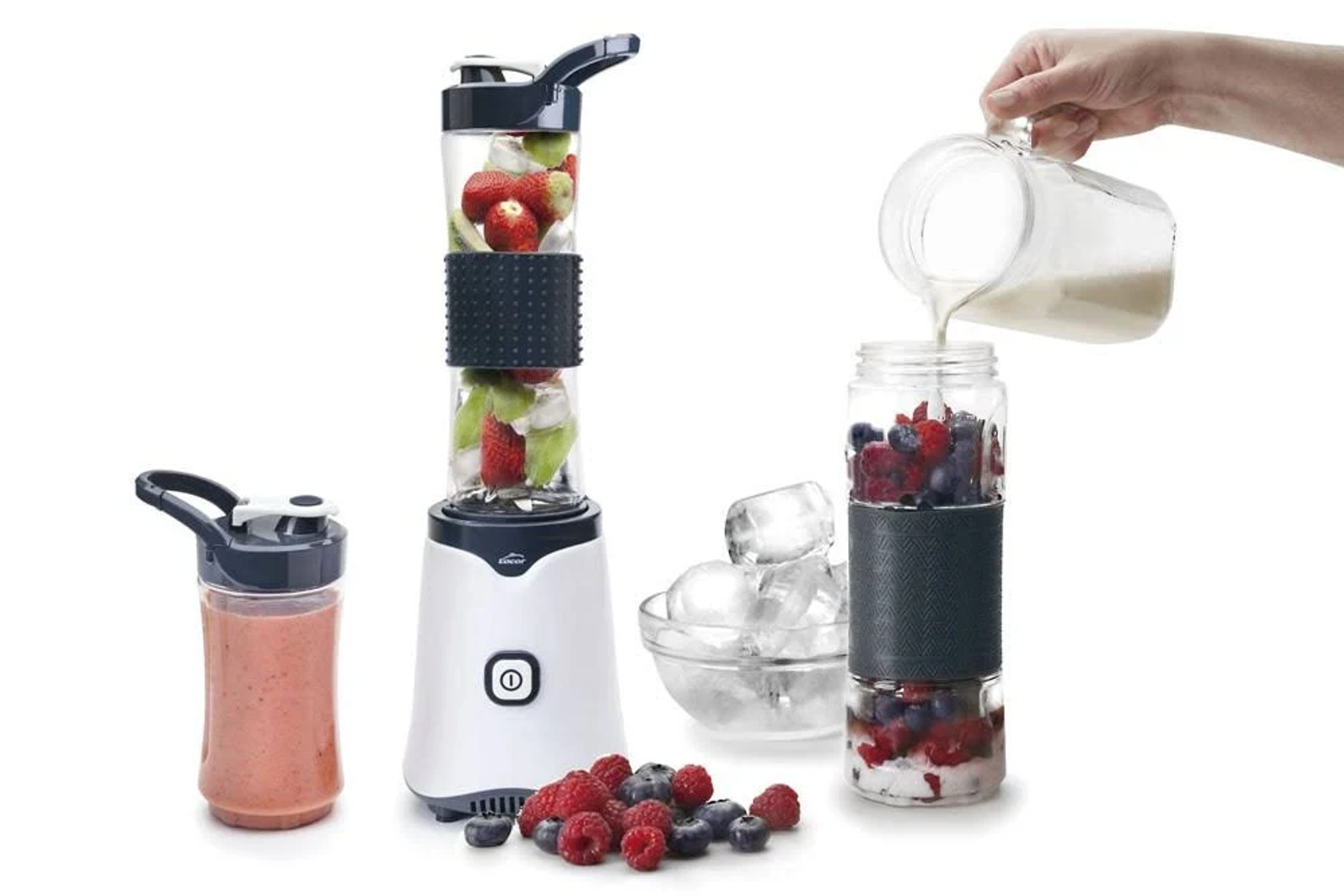 Un frullatore con frutta e ghiaccio, e una mano che versa liquido in un contenitore con bacche.