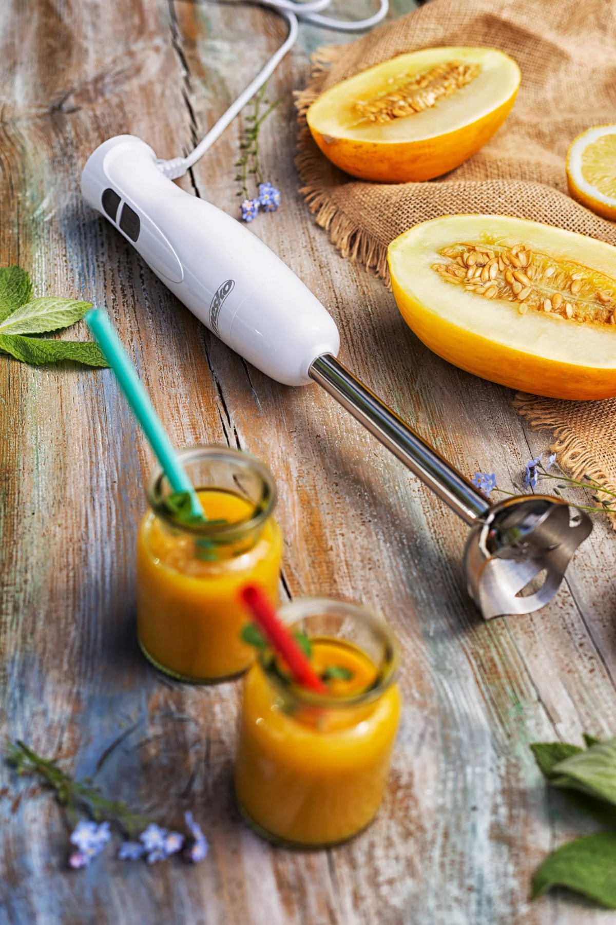 Blender ręczny i szklanki smoothie z owocami. Blender jest biały.