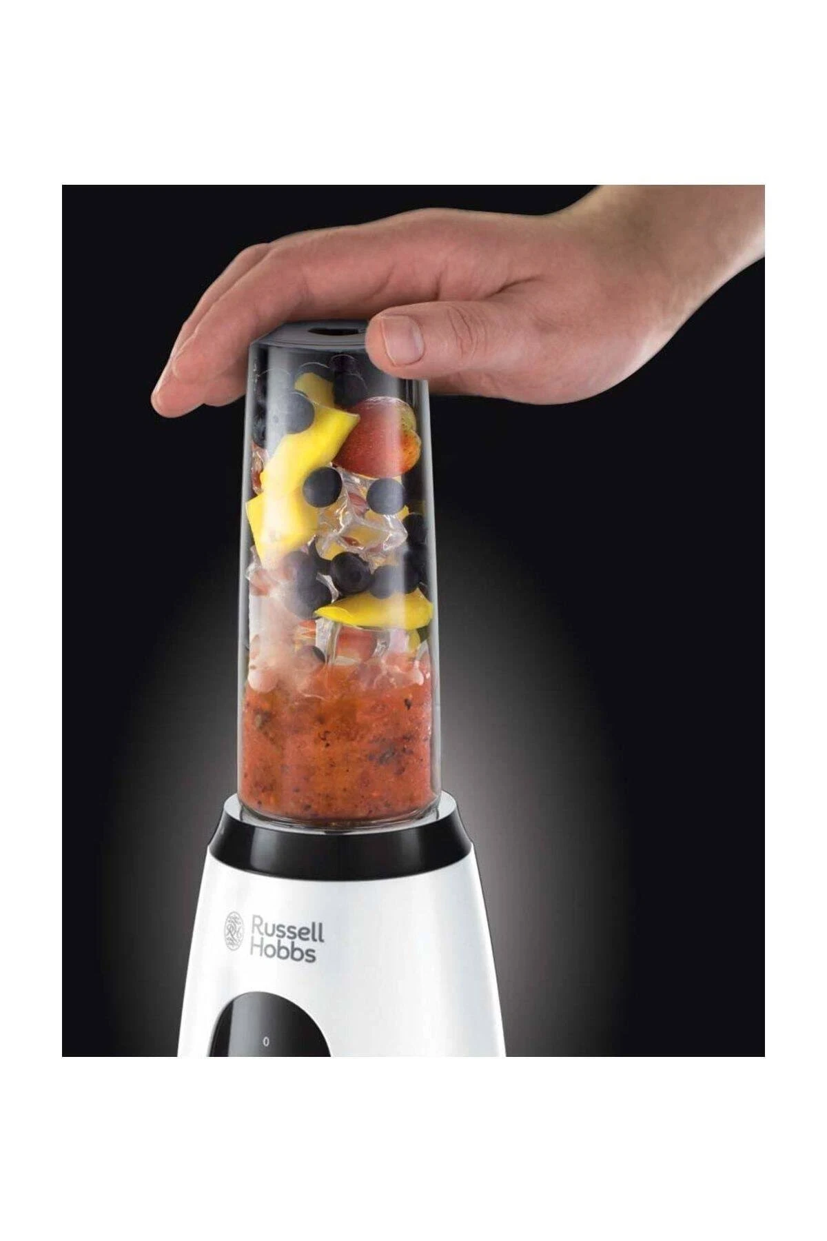 Bir el, meyve ve buz ile bir blender tutuyor. Blender beyaz ve siyahtır.
