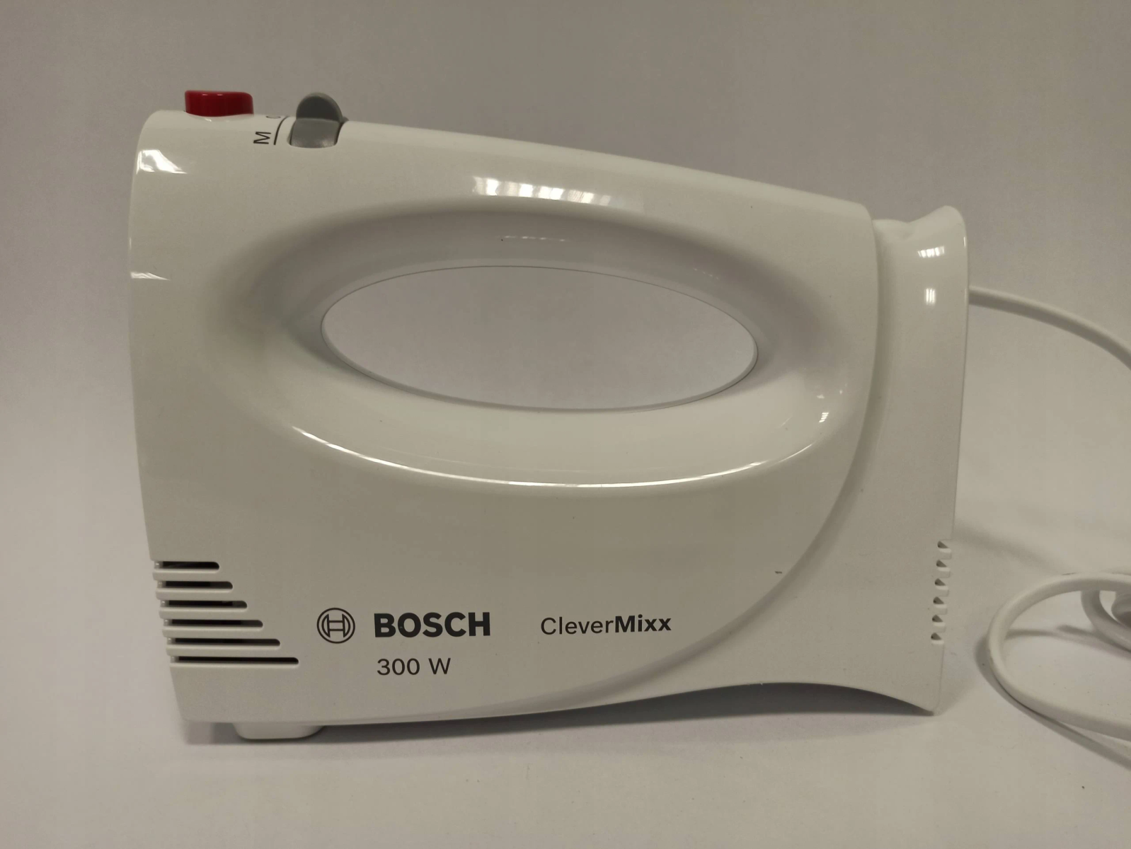 White hand mixer on a white surface. Red power button. Bosch CleverMixx brand.