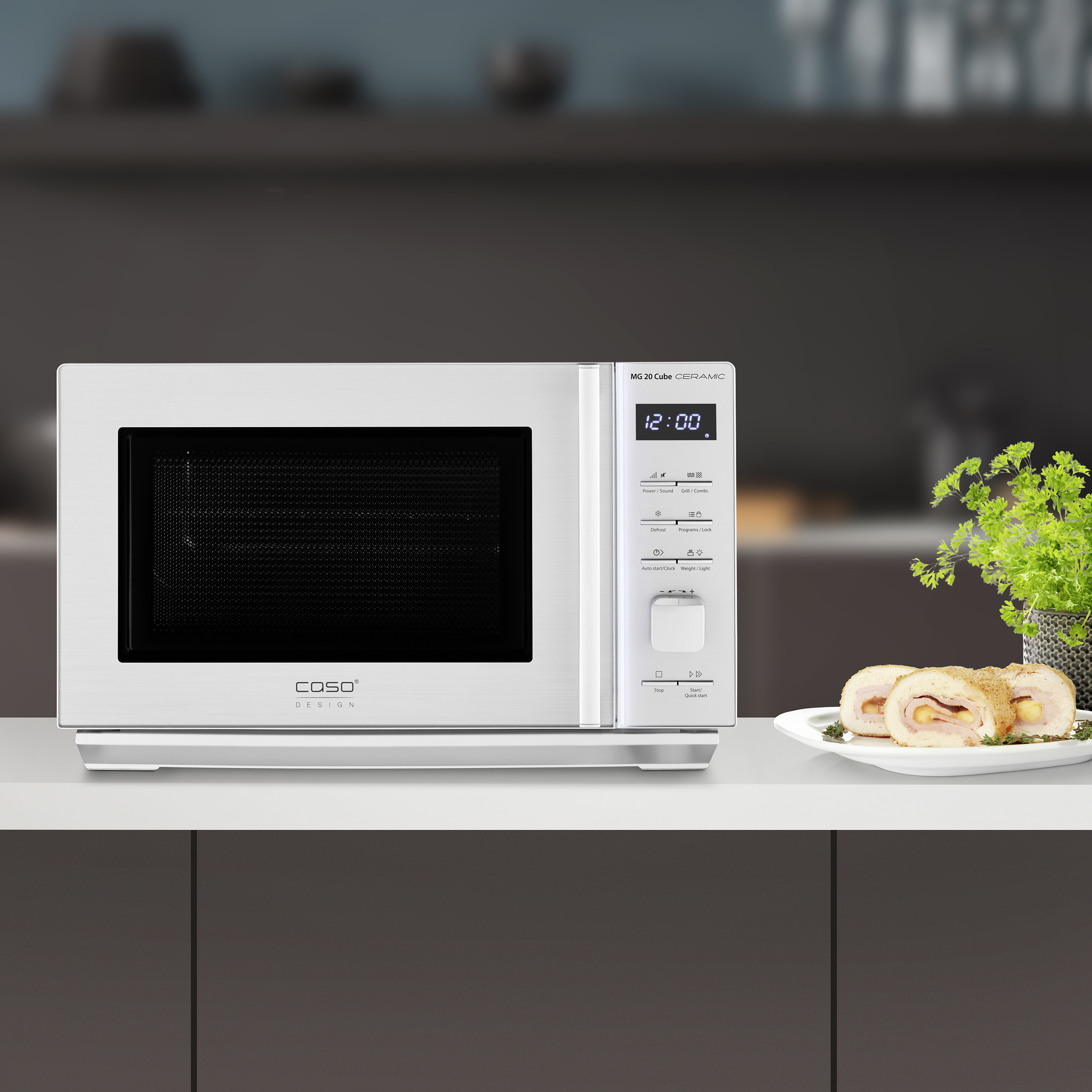Forno a microonde bianco con display digitale che mostra le 12:00. Un piatto di cibo a destra.