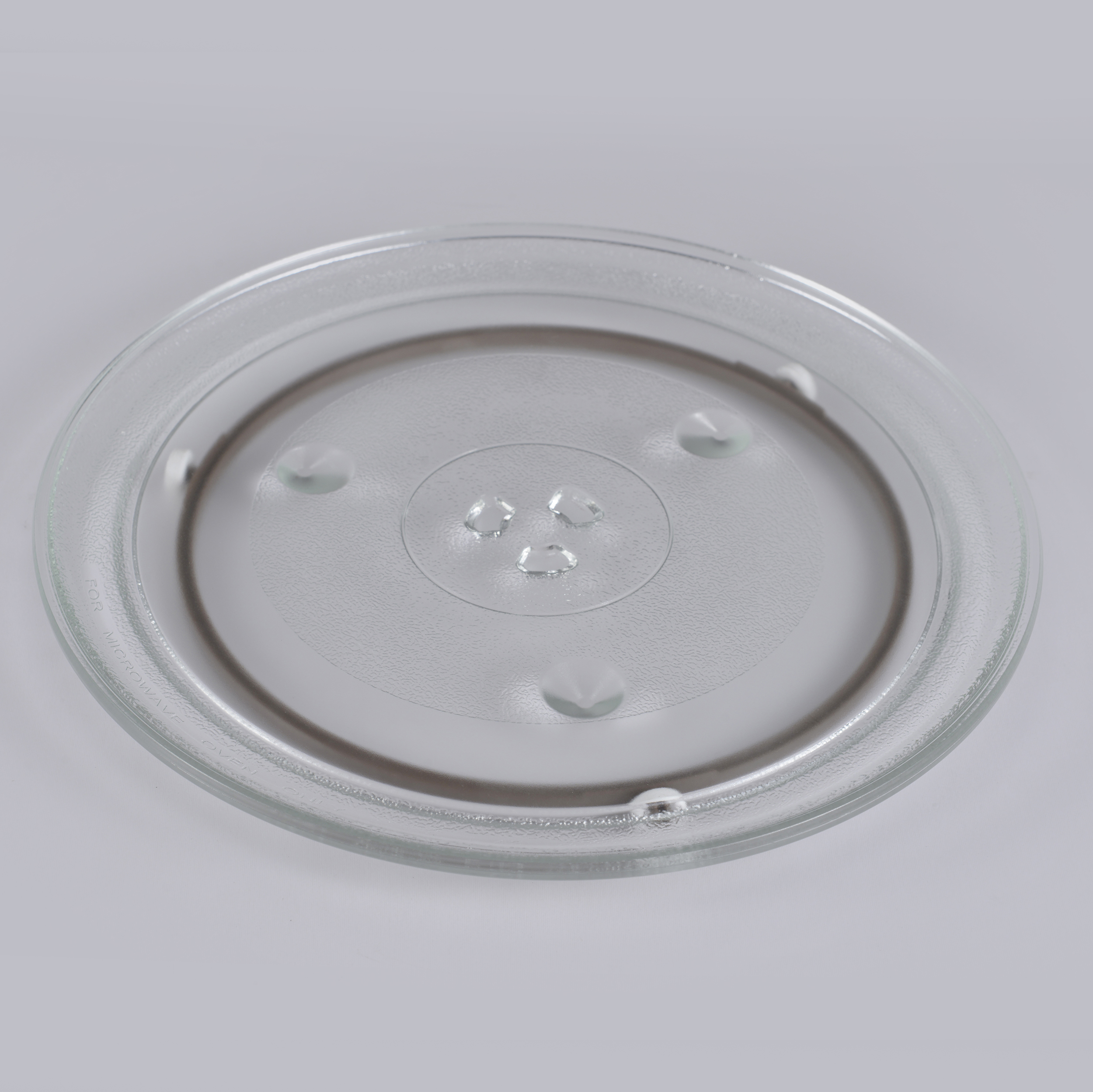 Klare Mikrowellenplatte aus Glas. Mit geriffeltem Rand und drei kleinen Erhebungen in der Mitte.