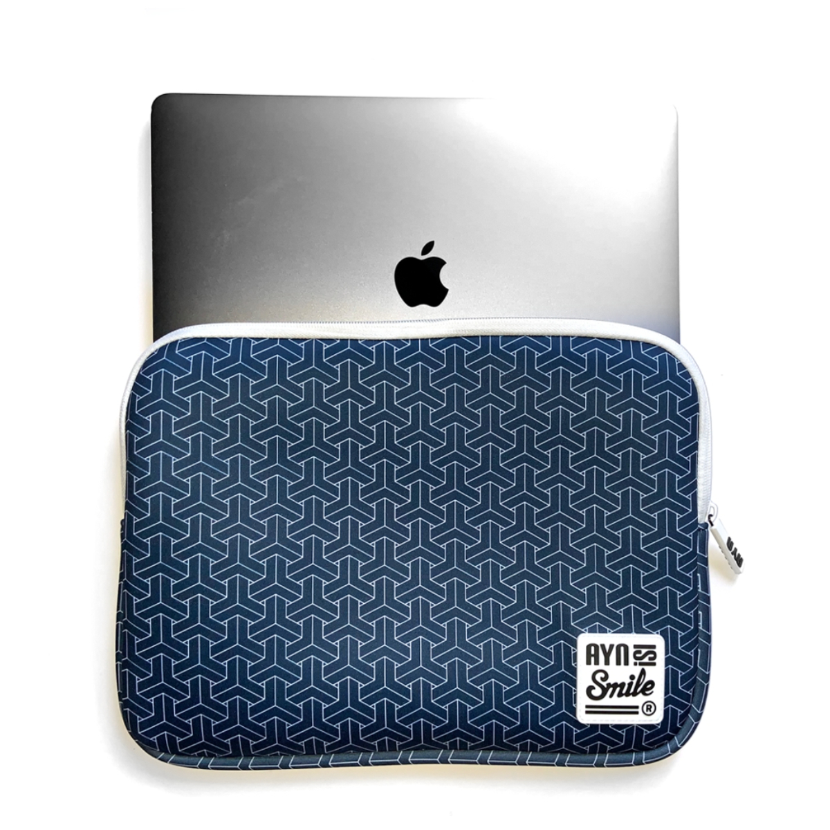 Un portátil en una funda para portátil con estampado azul marino. La funda tiene cremallera y un logo.