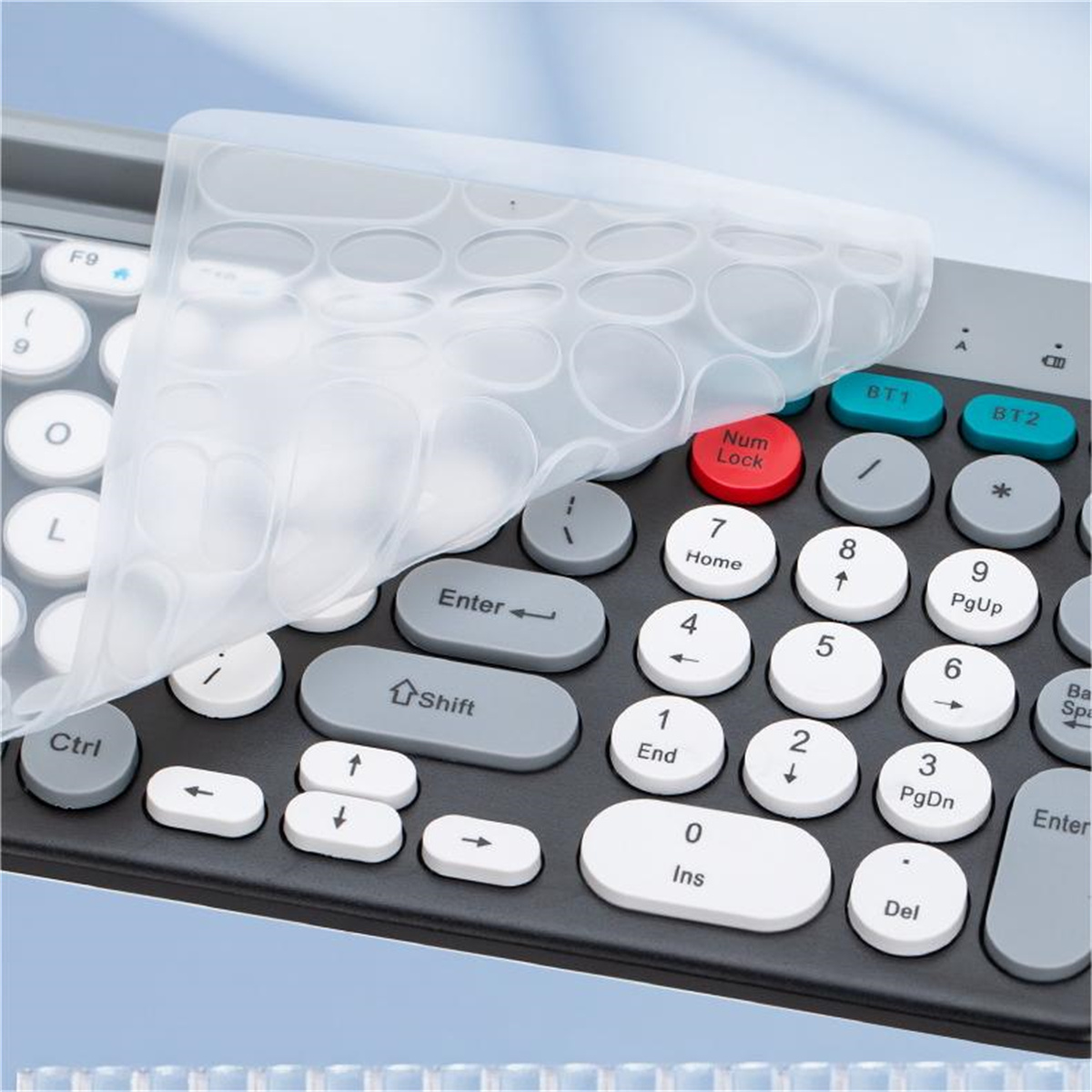 Teclado con cubierta, teclas blancas y grises. Algunas teclas tienen etiquetas de color. La cubierta está parcialmente quitada.