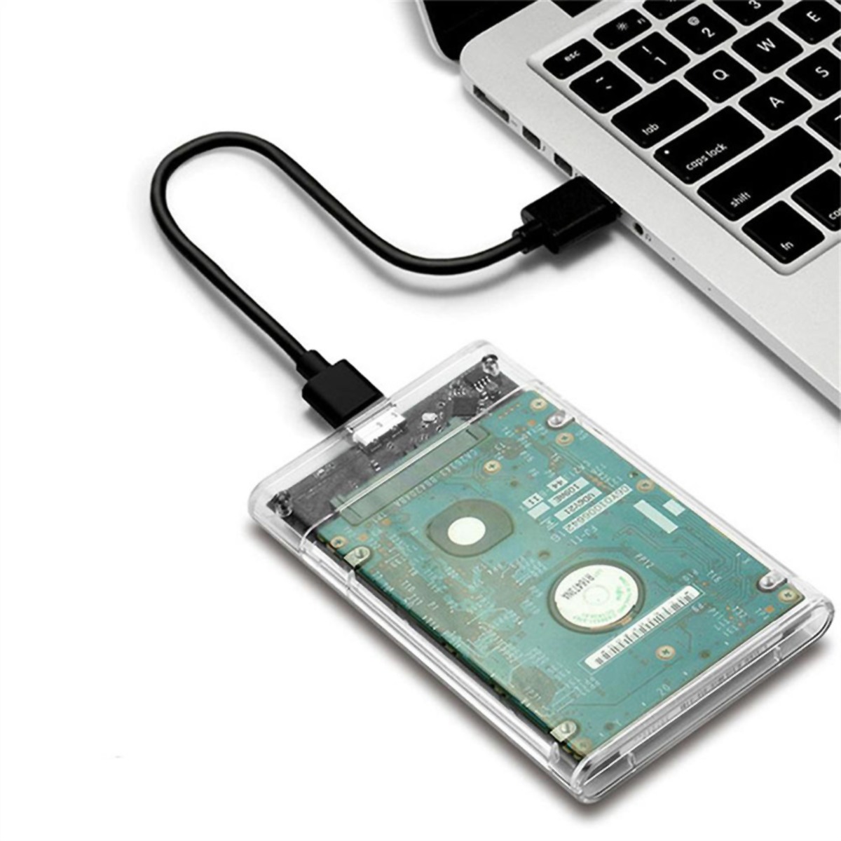 Una laptop conectada a un disco duro externo mediante un cable USB negro, sobre una superficie blanca.