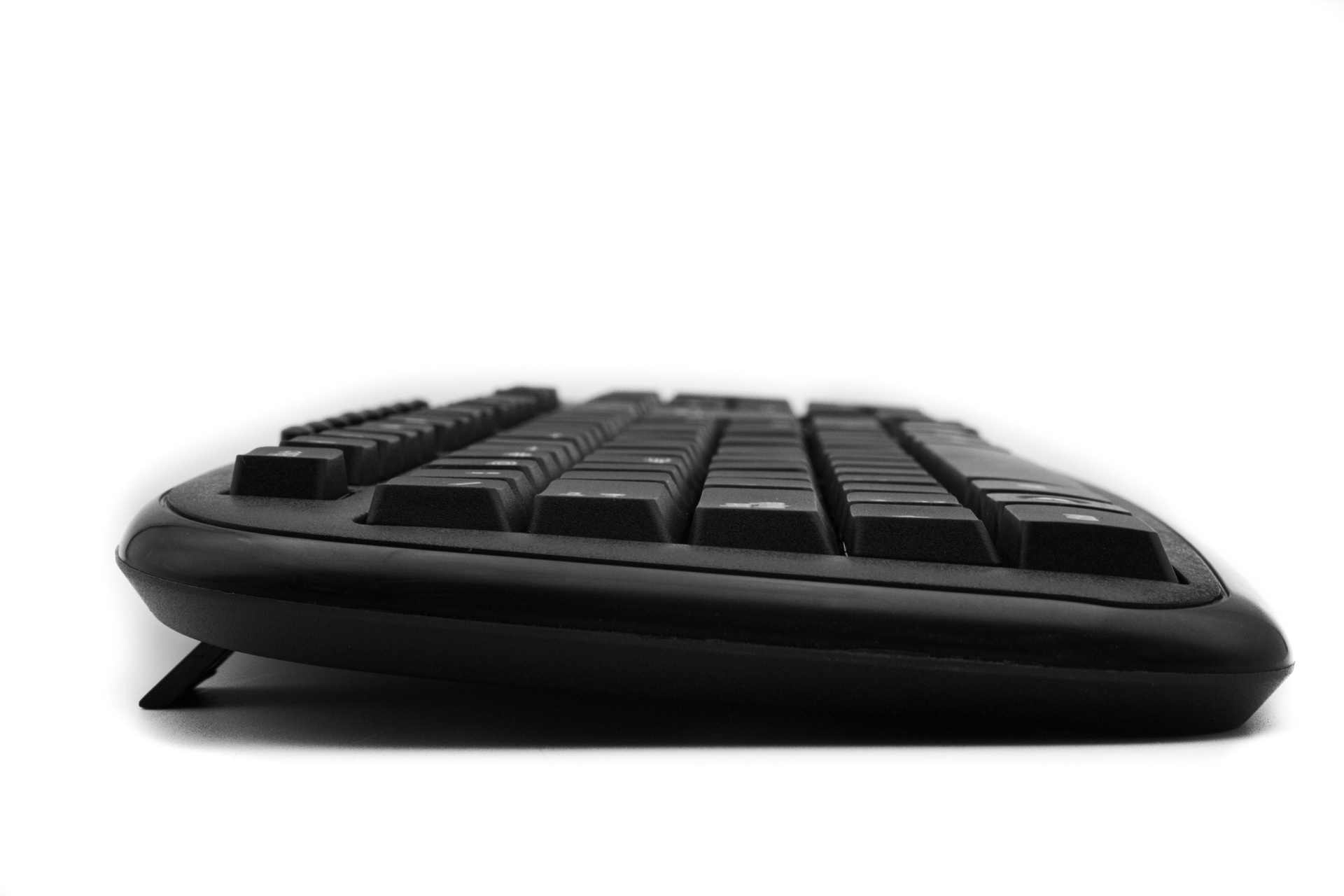 Teclado ergonómico negro con diseño curvo y patas elevadas.