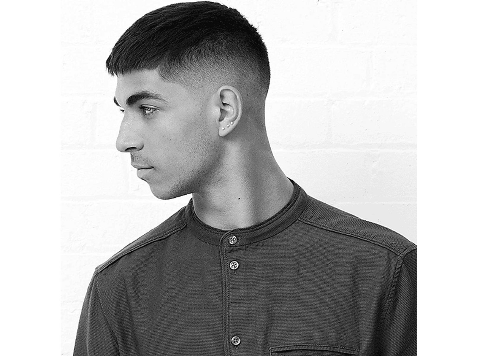 Un hombre de perfil, con corte de pelo corto. Lleva una camisa oscura.