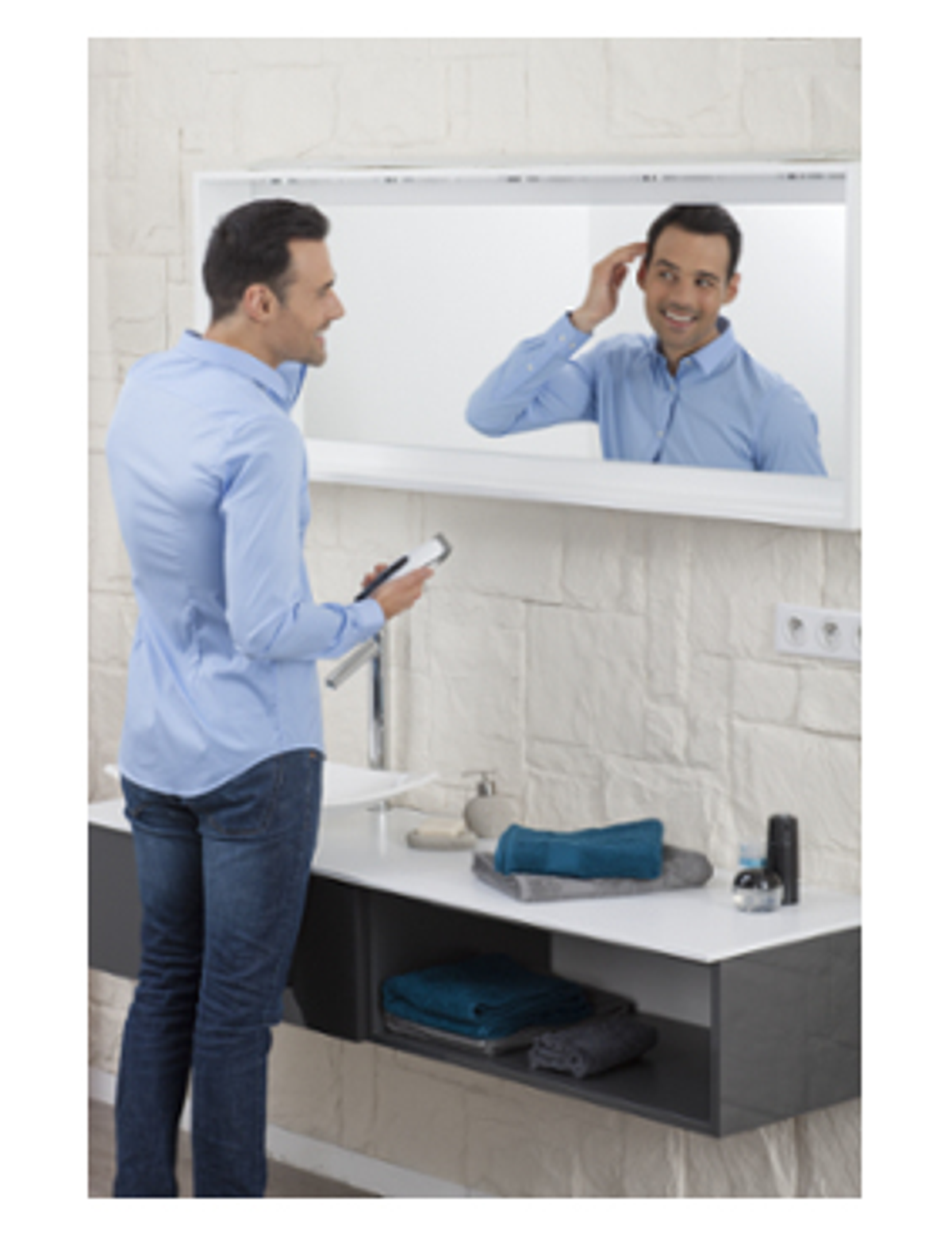 Hombre en camisa azul mirándose al espejo, peinándose, baño.