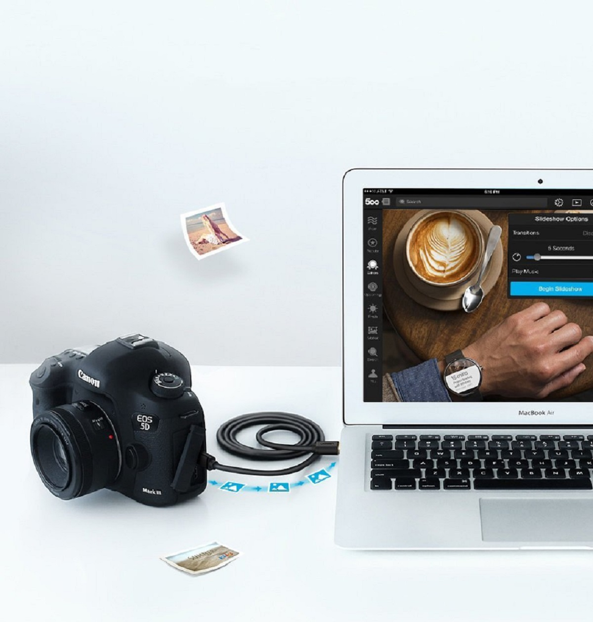 Aparat Canon podłączony do laptopa. Trwa przesyłanie obrazów. Białe tło.