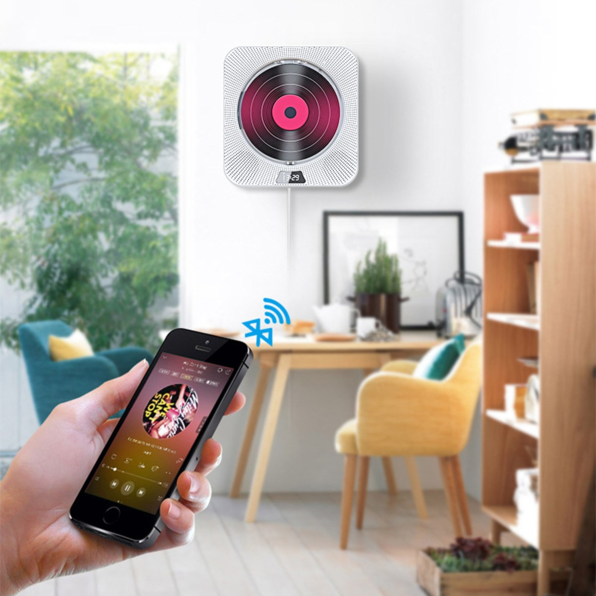 Una persona sosteniendo un smartphone conectado a un reproductor de CD montado en la pared con Bluetooth.