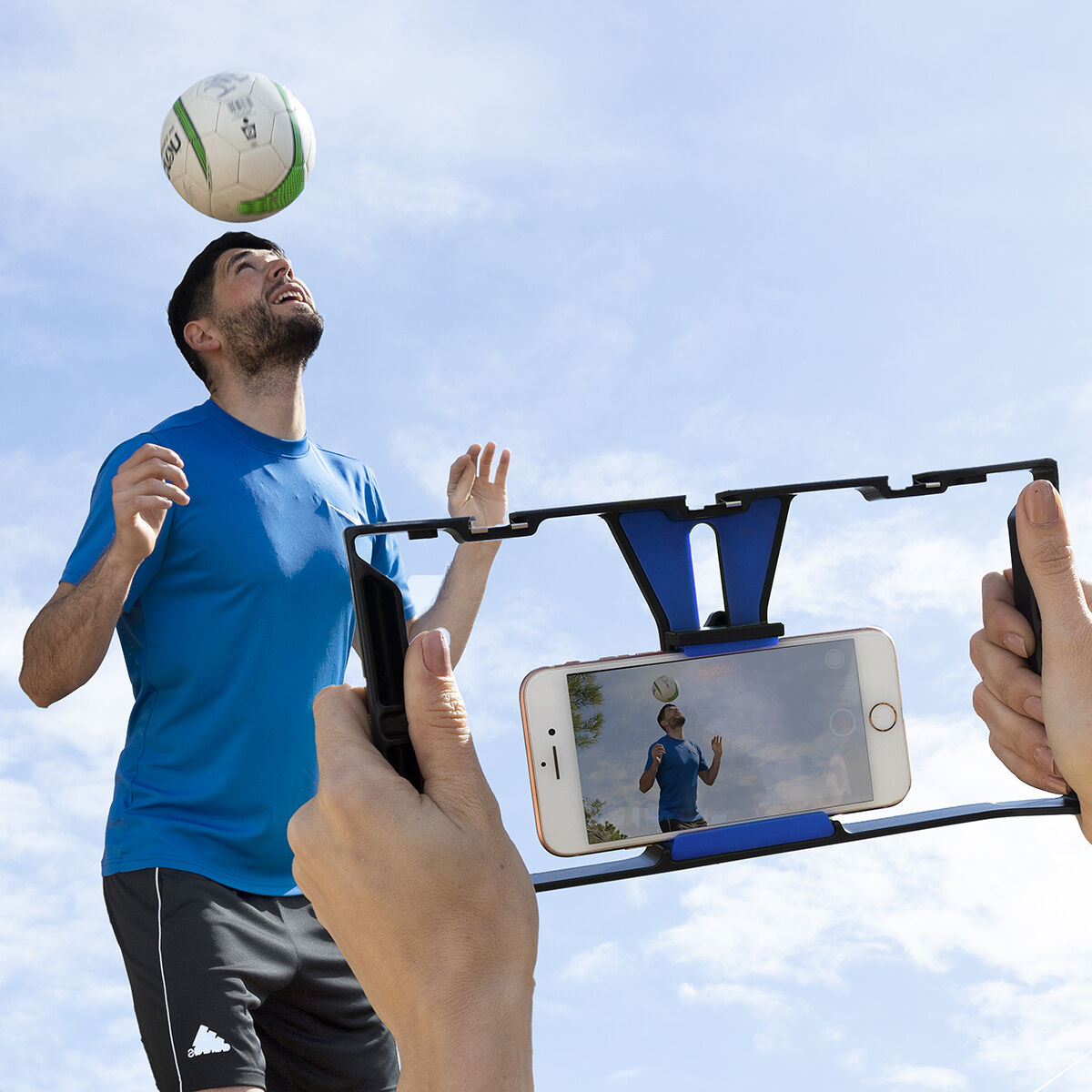 Un uomo viene filmato da un telefono in un supporto mentre fa giocoleria con un pallone.