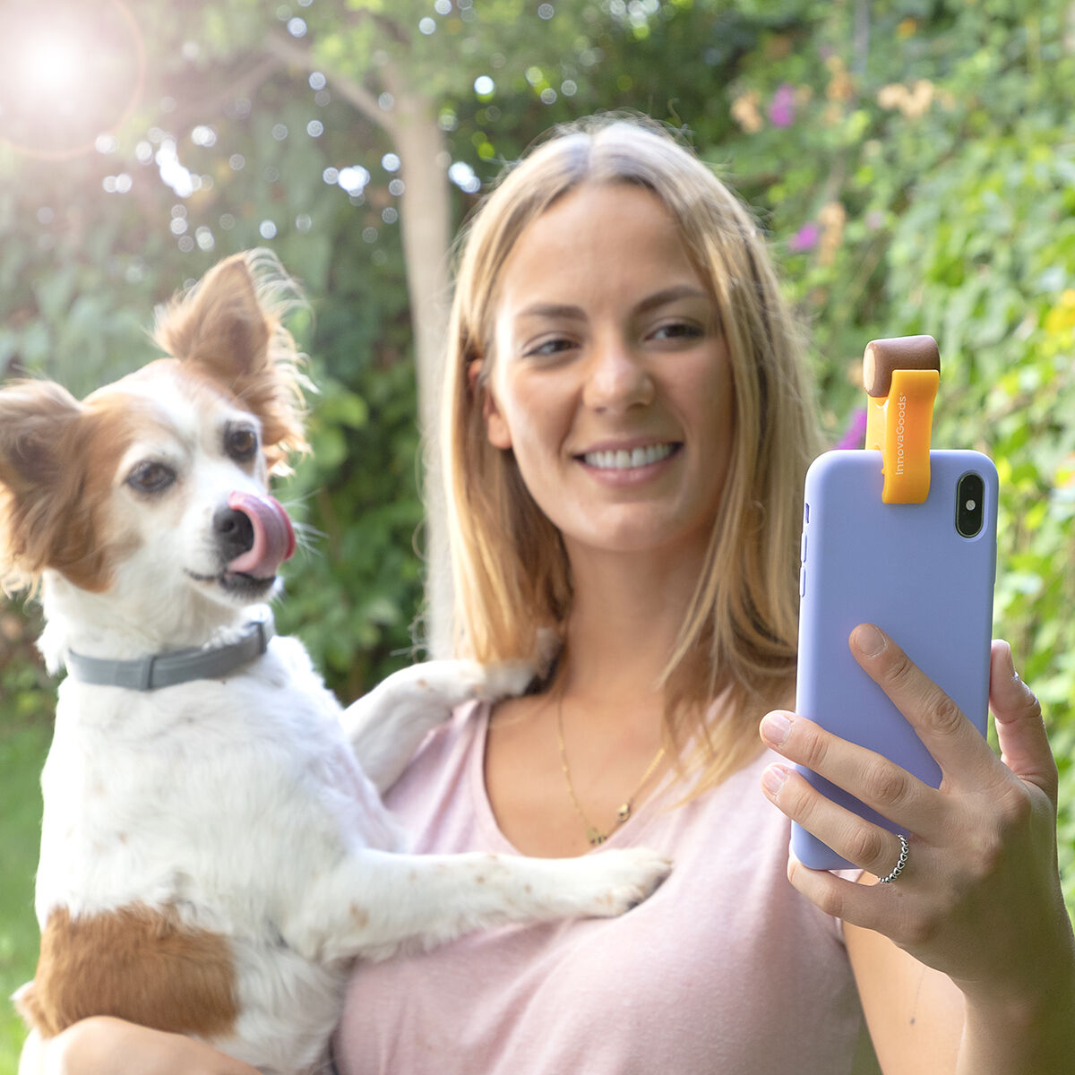 Donna bionda con il suo cane, che fa un selfie con un telefono e un accessorio.