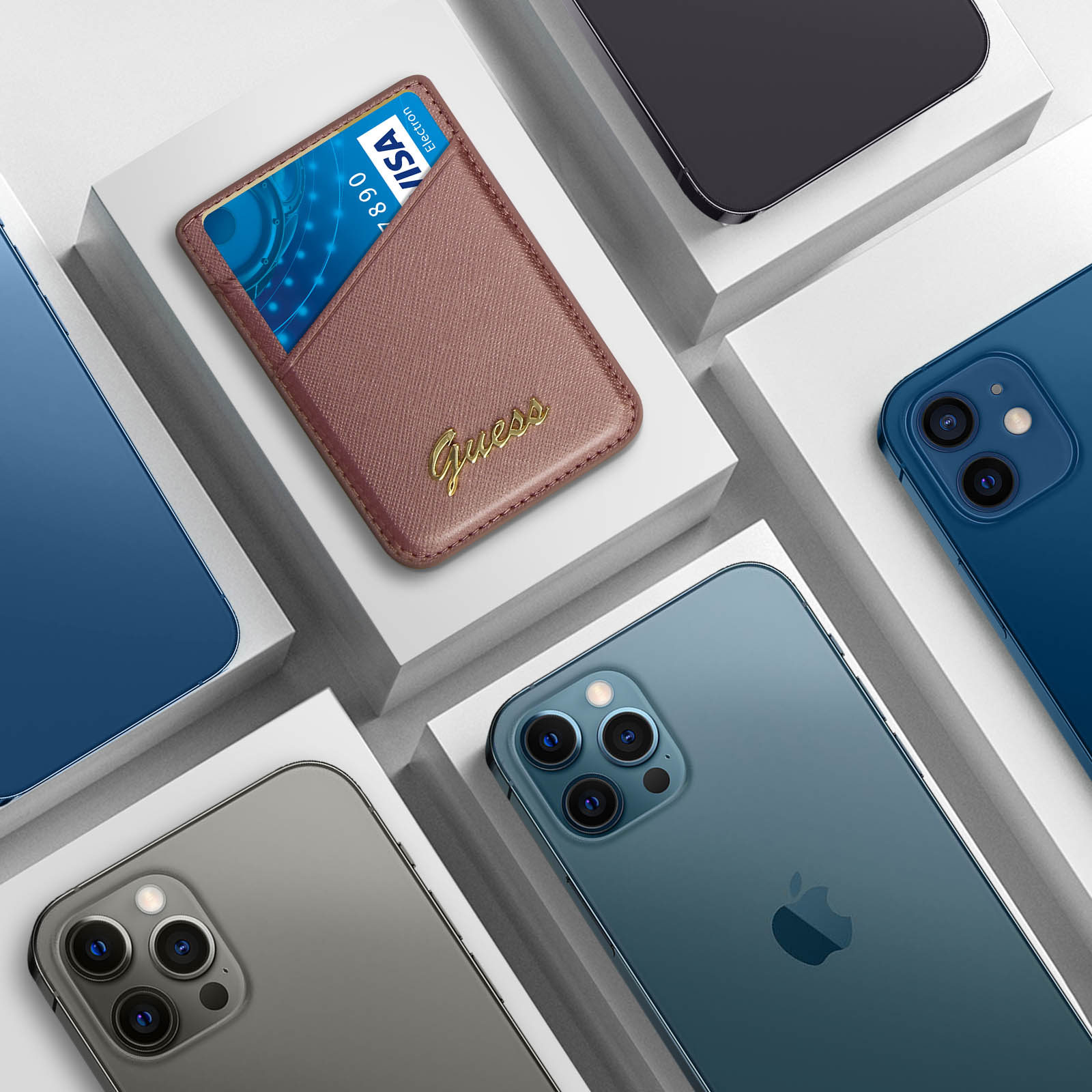 Mehrere Smartphones und ein Guess Kartenhalter auf weißen Plattformen. Telefone in Blau, Grau und Schwarz.