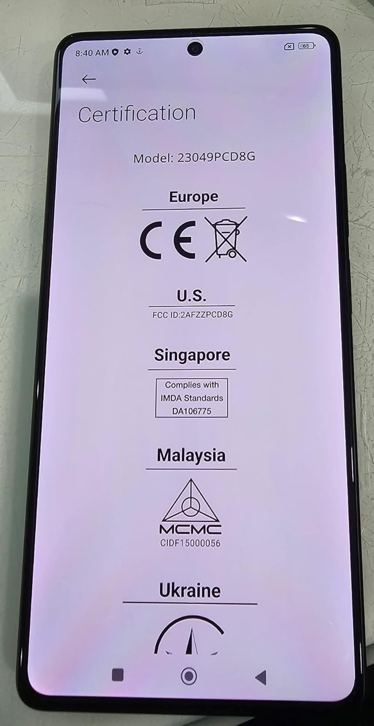 Ekran smartfona pokazujący szczegóły certyfikacji i logo z Europy, USA, Singapuru, Malezji, Ukrainy.