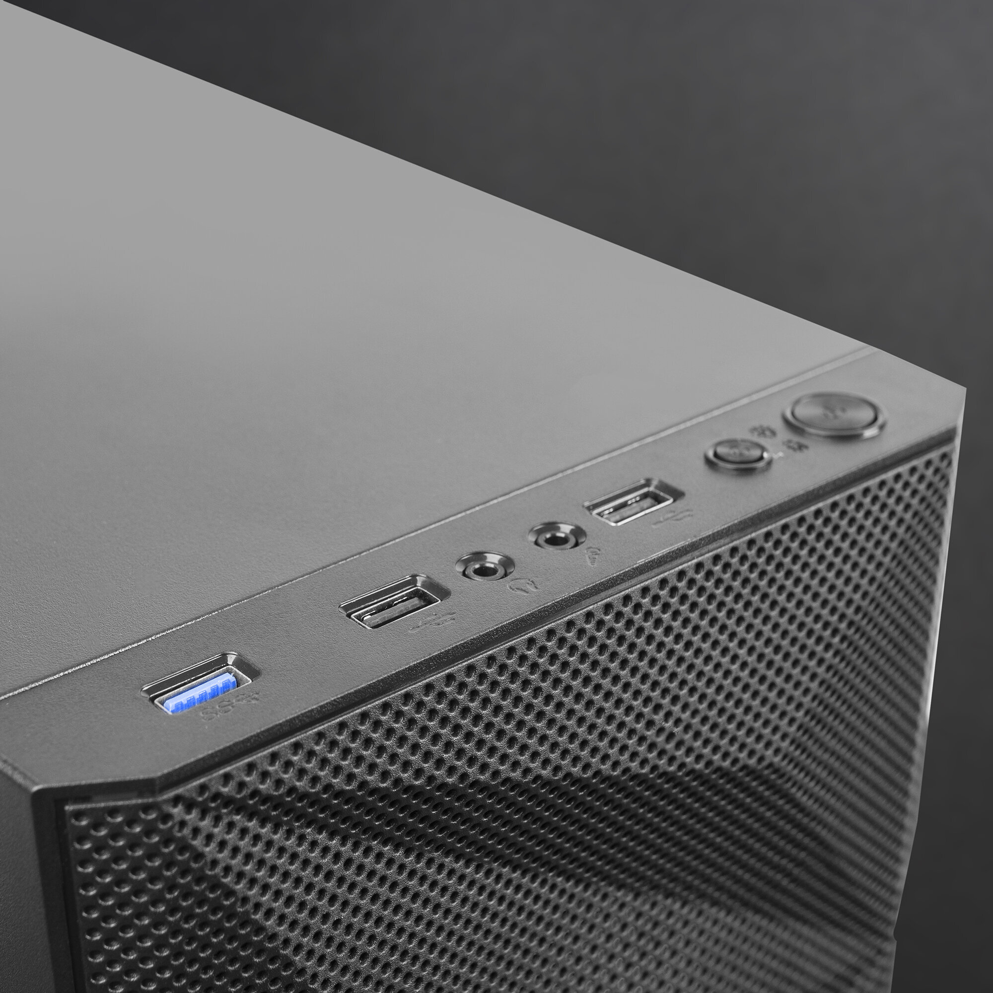 Primer plano de la parte superior de una caja de computadora negra, que muestra puertos y botones sobre un fondo oscuro.