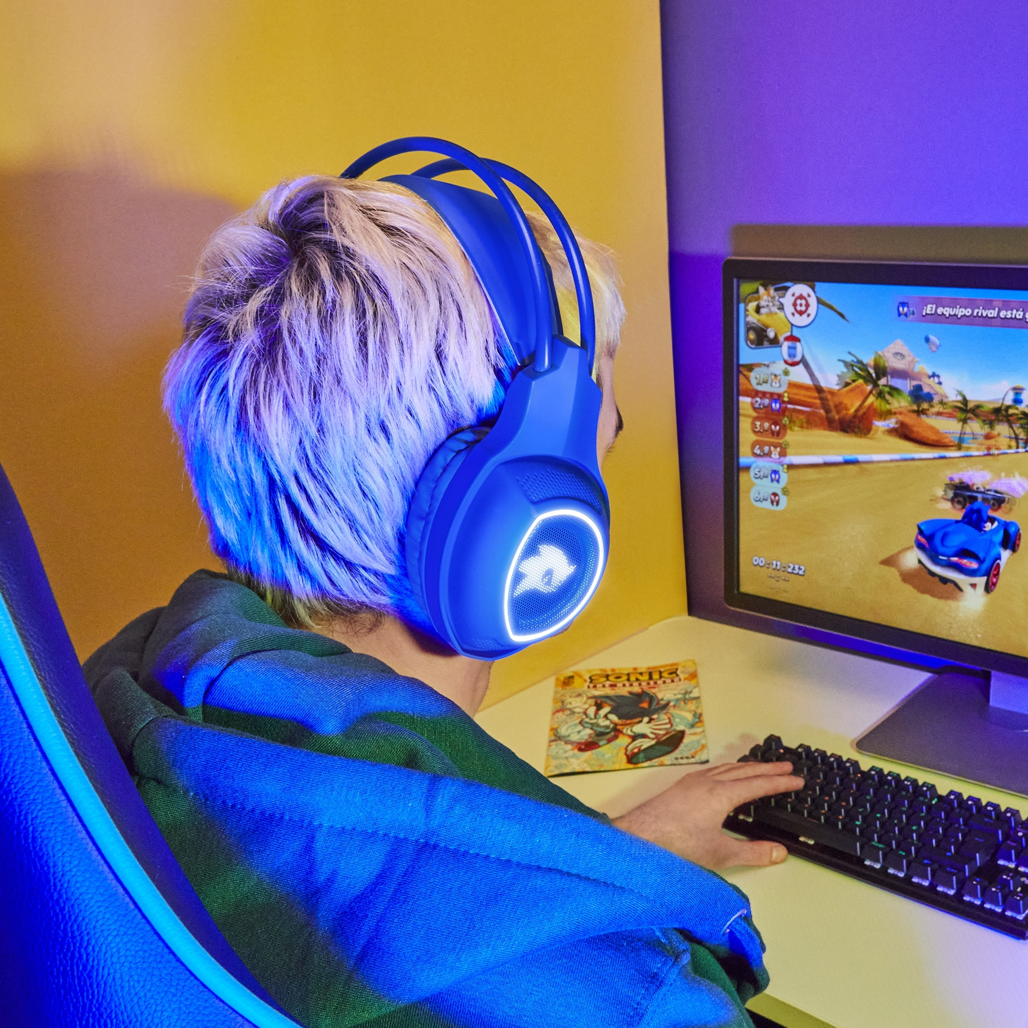 Persona con auriculares de juego azules, jugando un juego de carreras en un monitor.