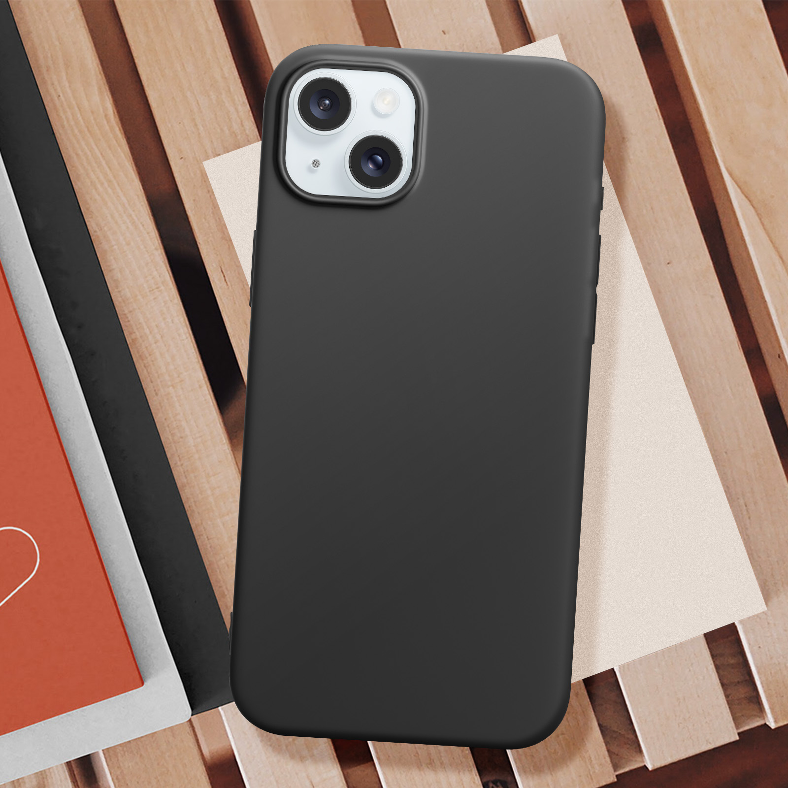 Custodia nera per telefono su superficie in legno con un quaderno.