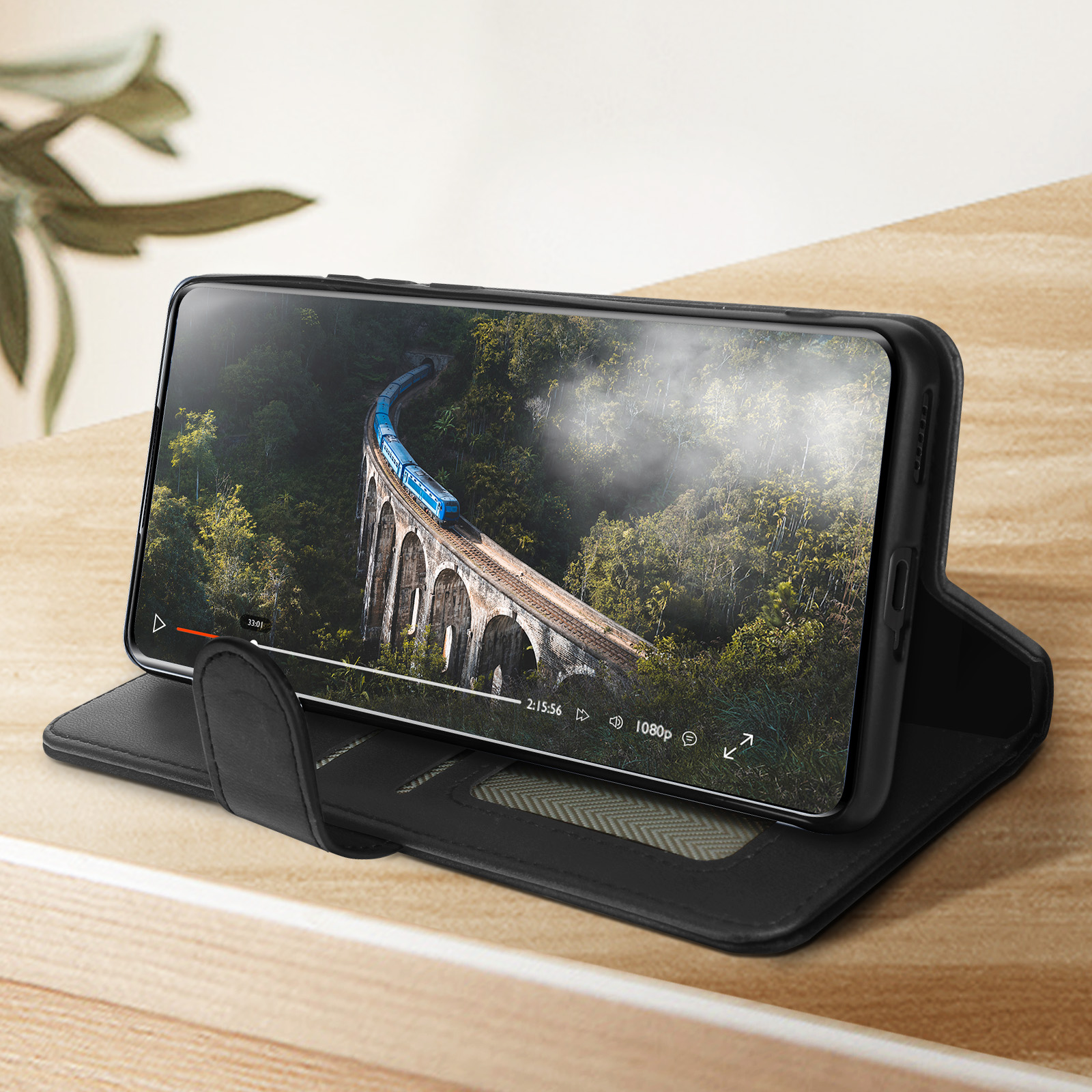 Smartphone zeigt Zug auf Brücke, in schwarzer Lederhülle, auf Holzoberfläche.