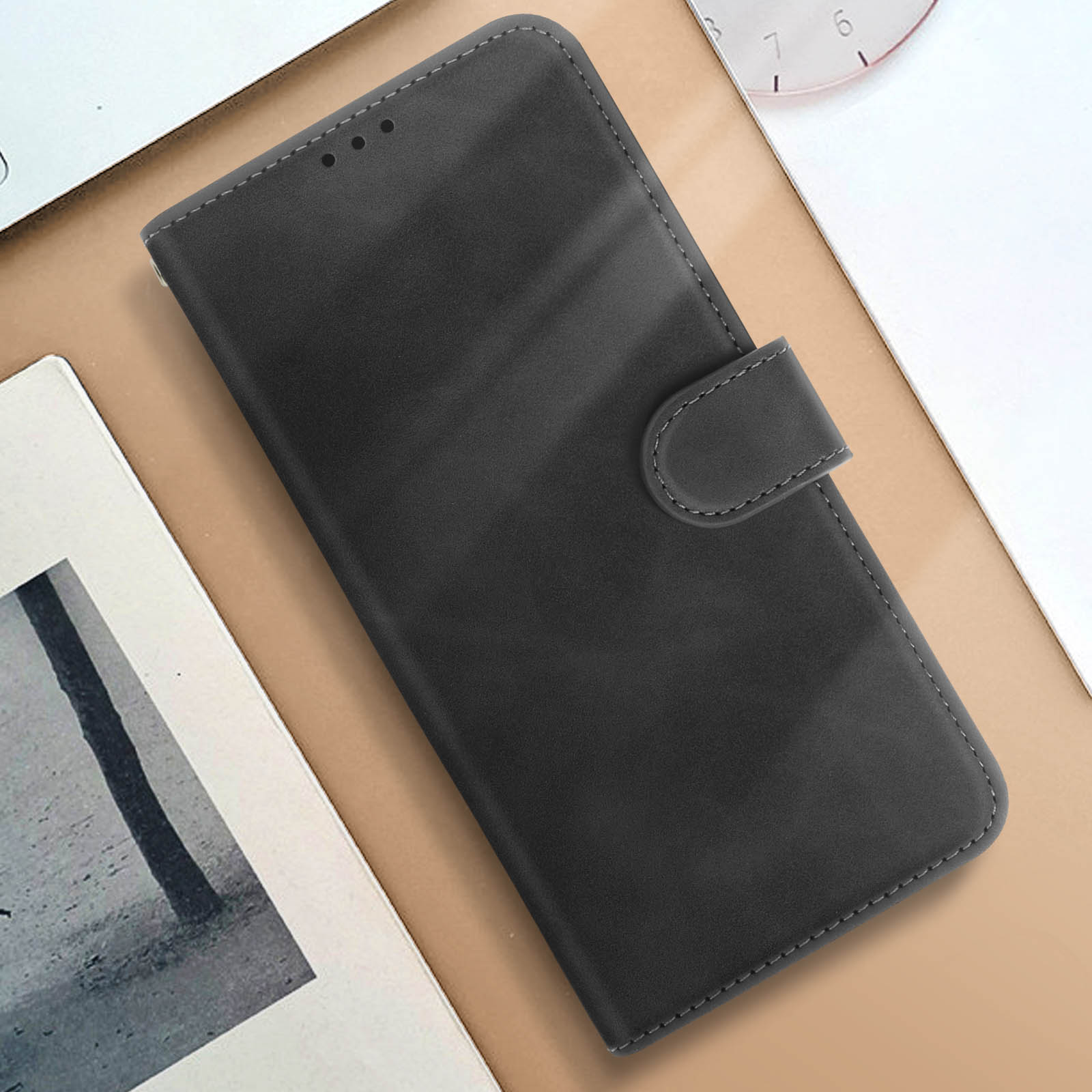 Custodia per telefono nera con texture simile alla pelle e chiusura magnetica. Sfondo beige.