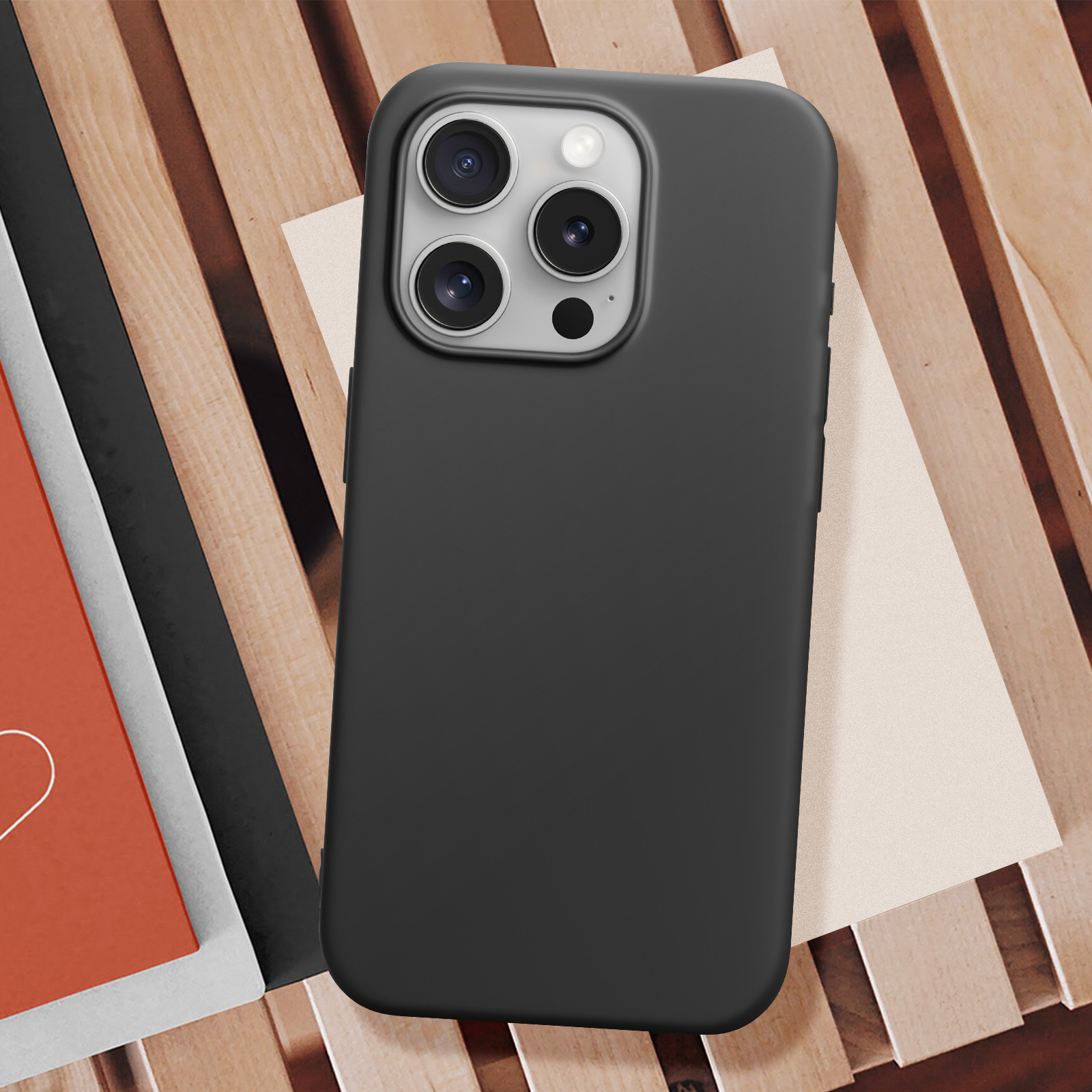 Una custodia nera con tre lenti della fotocamera, su una superficie di legno.
