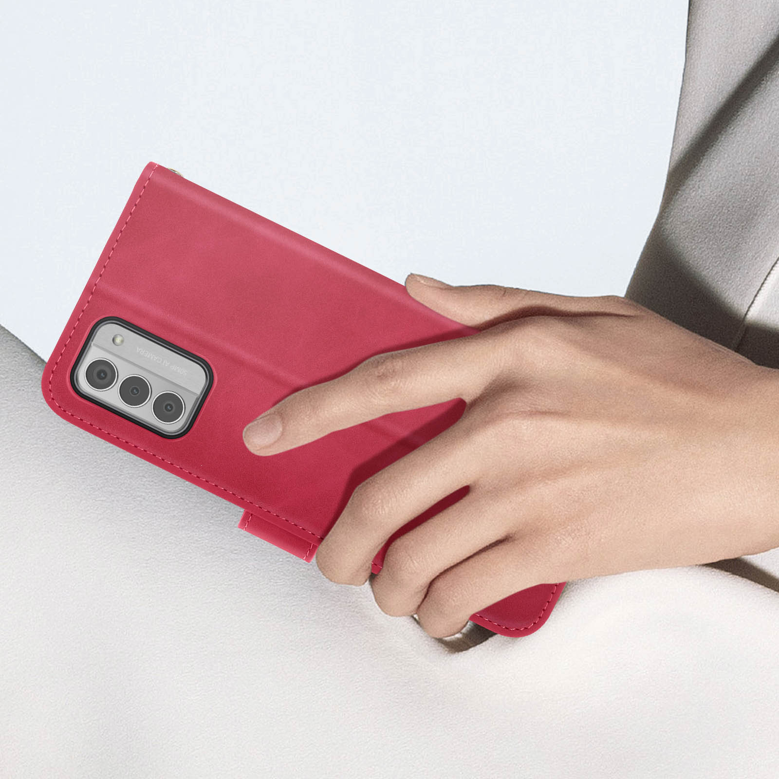 Donna che tiene una custodia per telefono rossa, con il telefono all'interno. Primo piano.